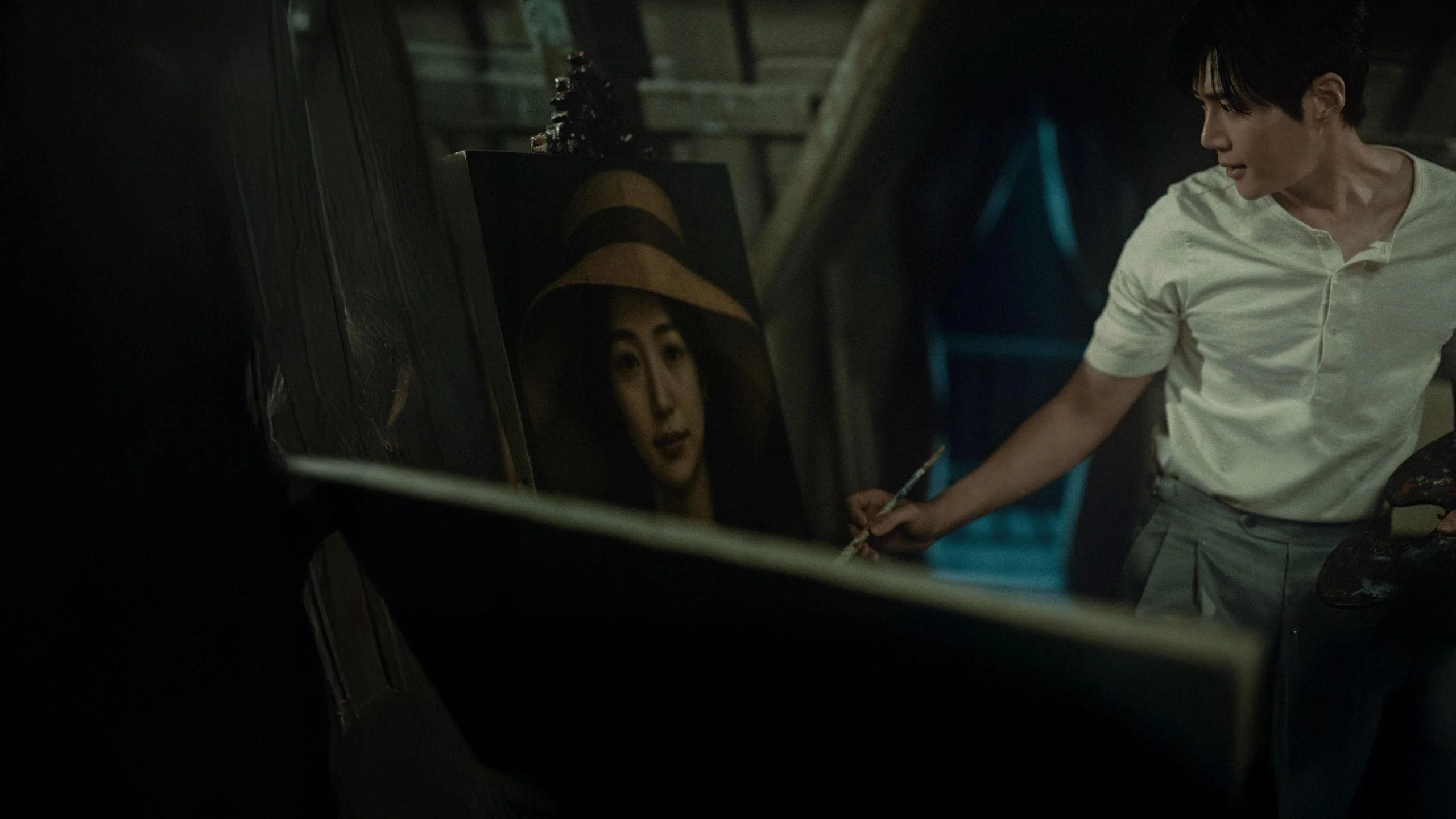 A painter stands beside a portrait in Disney+ promotional imagery for Portraits of Delusion.