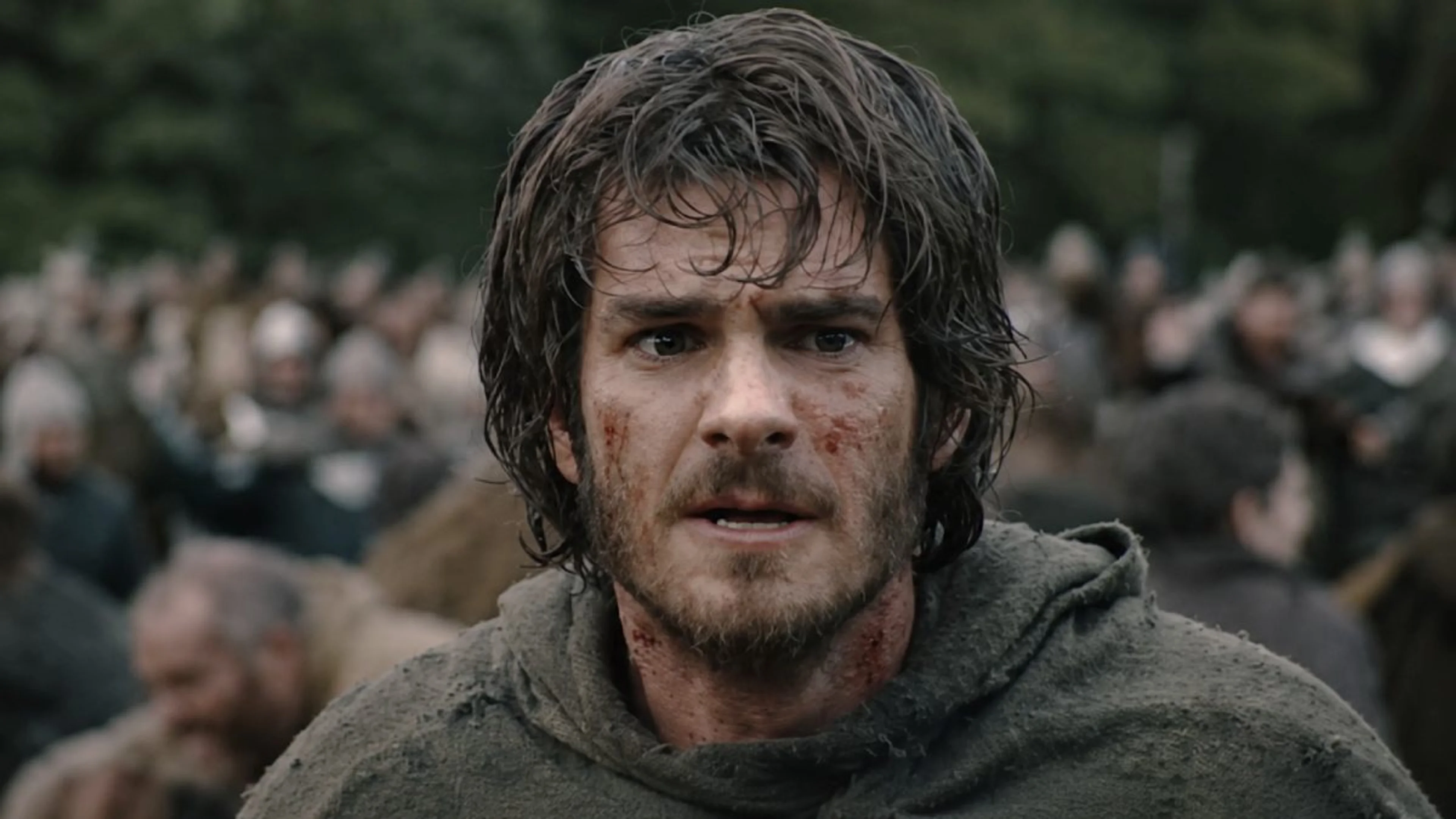 Andrew Garfield as the Ploughman has blood on his face, with a crowd behind him.