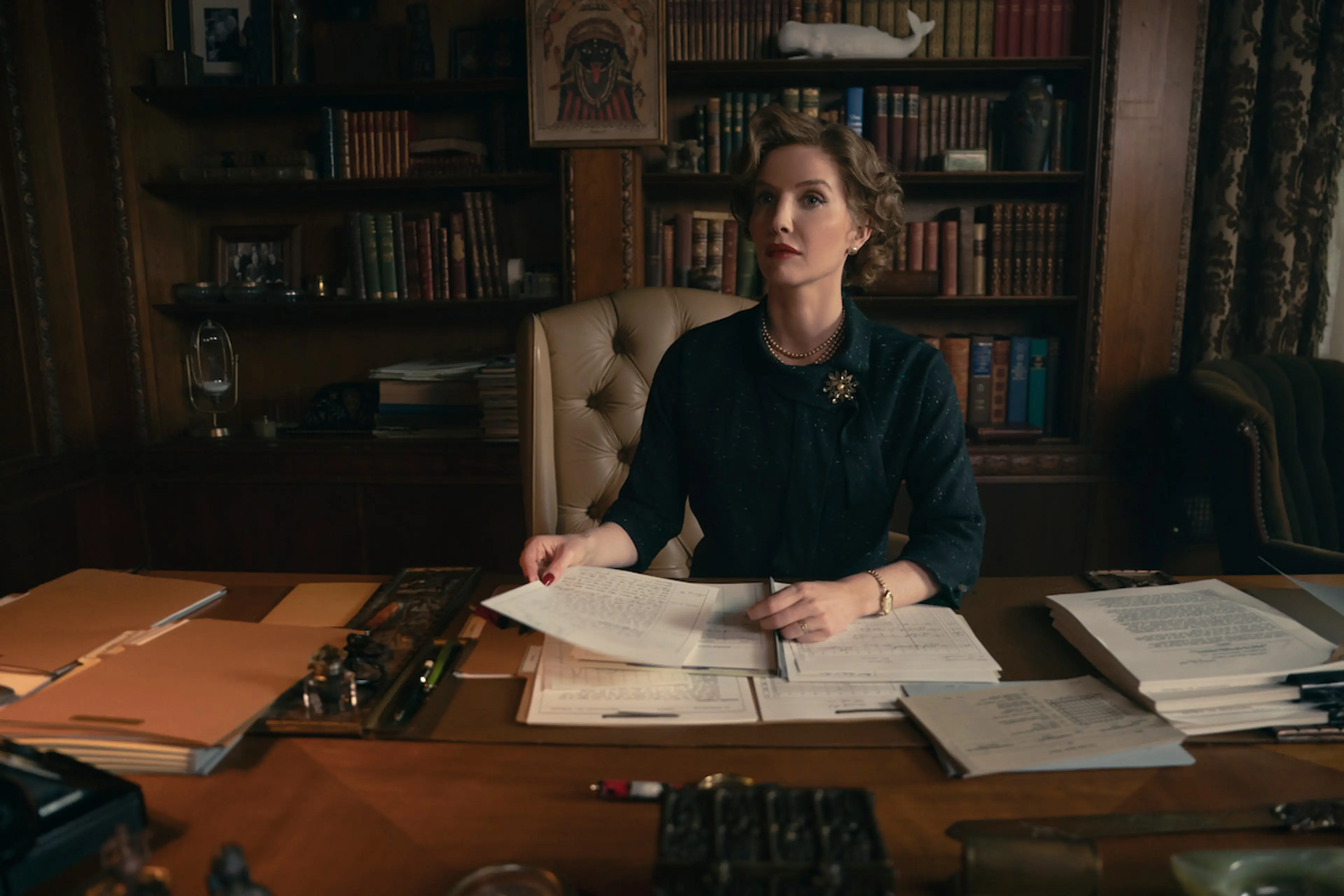 Annabelle Wallis as Christiana Morgan sits behind a desk covered with papers.