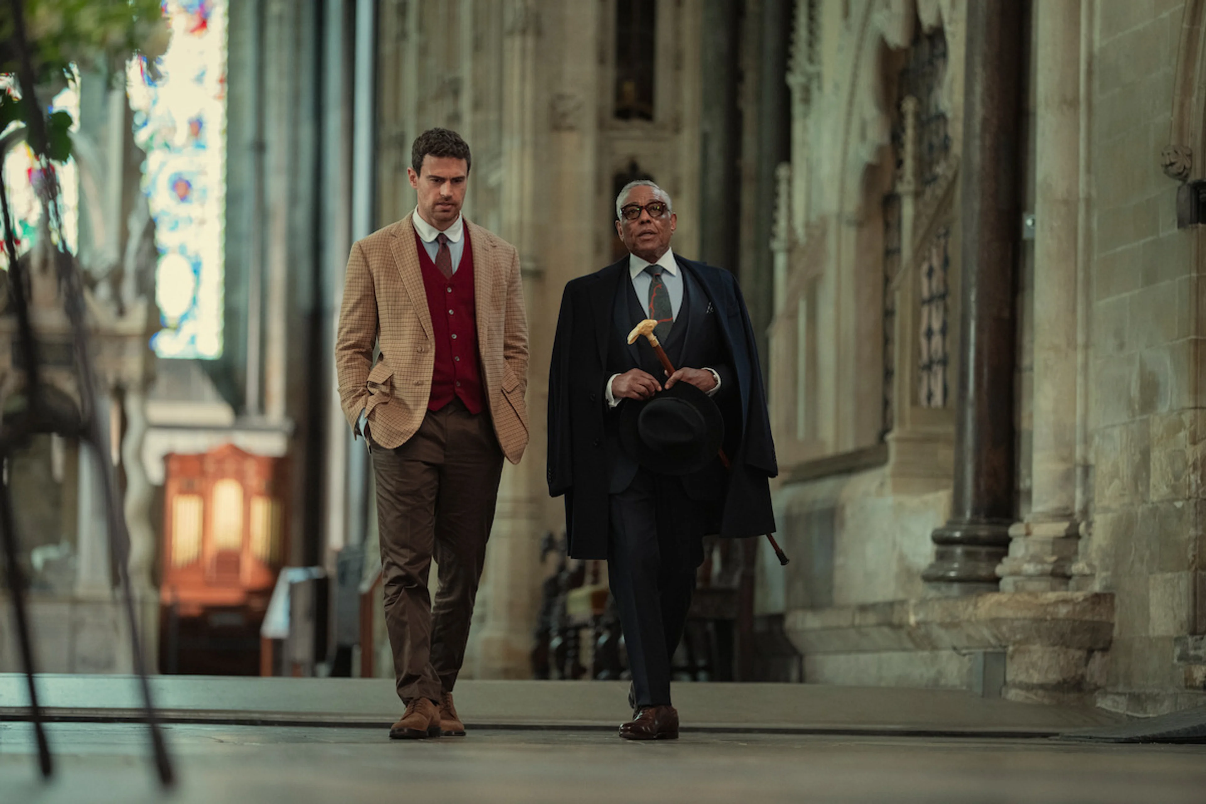 Theo James walks beside Giancarlo Esposito in a grand building in The Gentlemen Season 2.