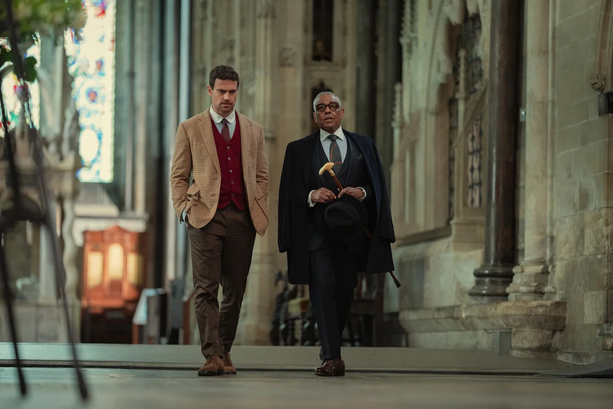 Theo James walks beside Giancarlo Esposito in a grand building in The Gentlemen Season 2.