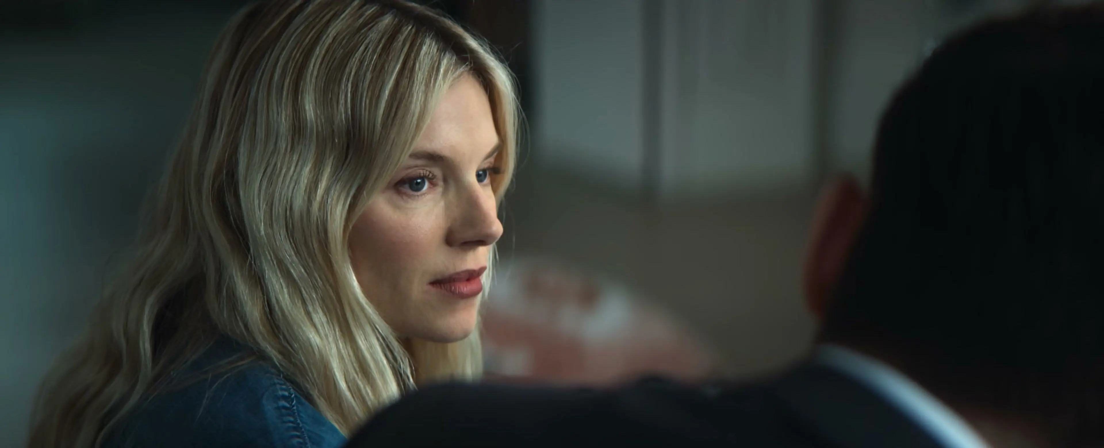 Sienna Miller as Carla Duval looks across a room in the WAR trailer.