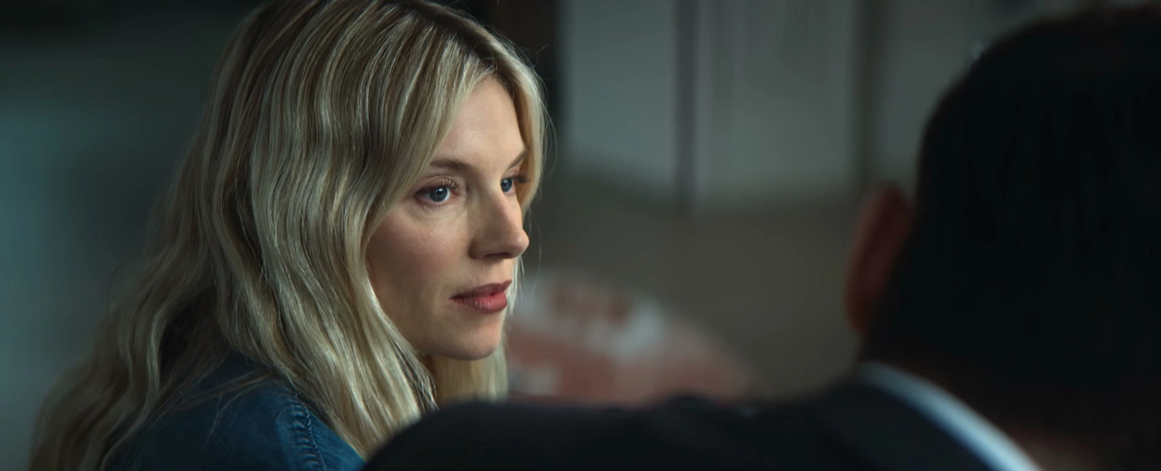 Sienna Miller as Carla Duval looks across a room in the WAR trailer.