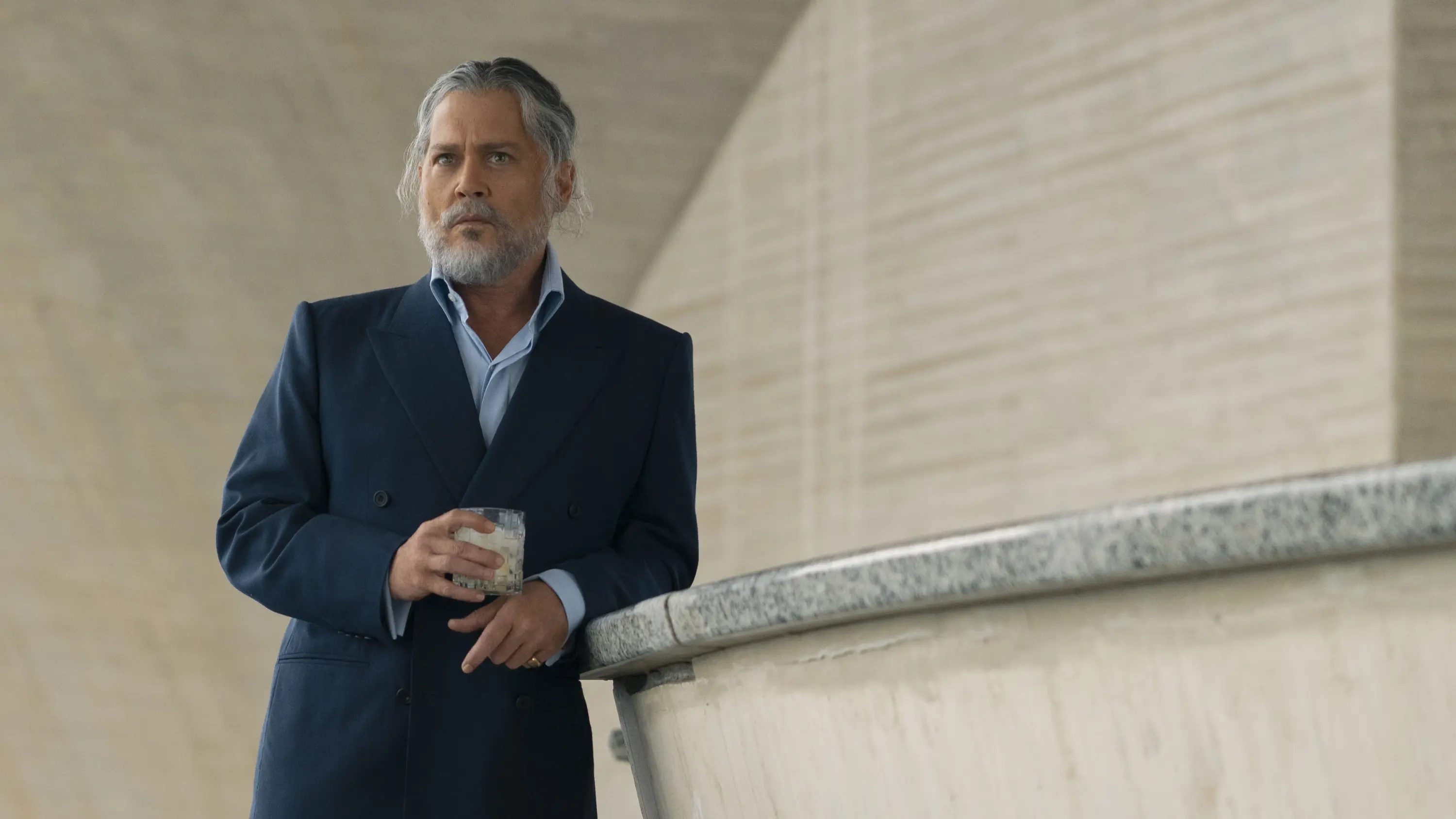 Johnny Depp, with gray hair and beard, holds a drink in an official Day Drinker film still.