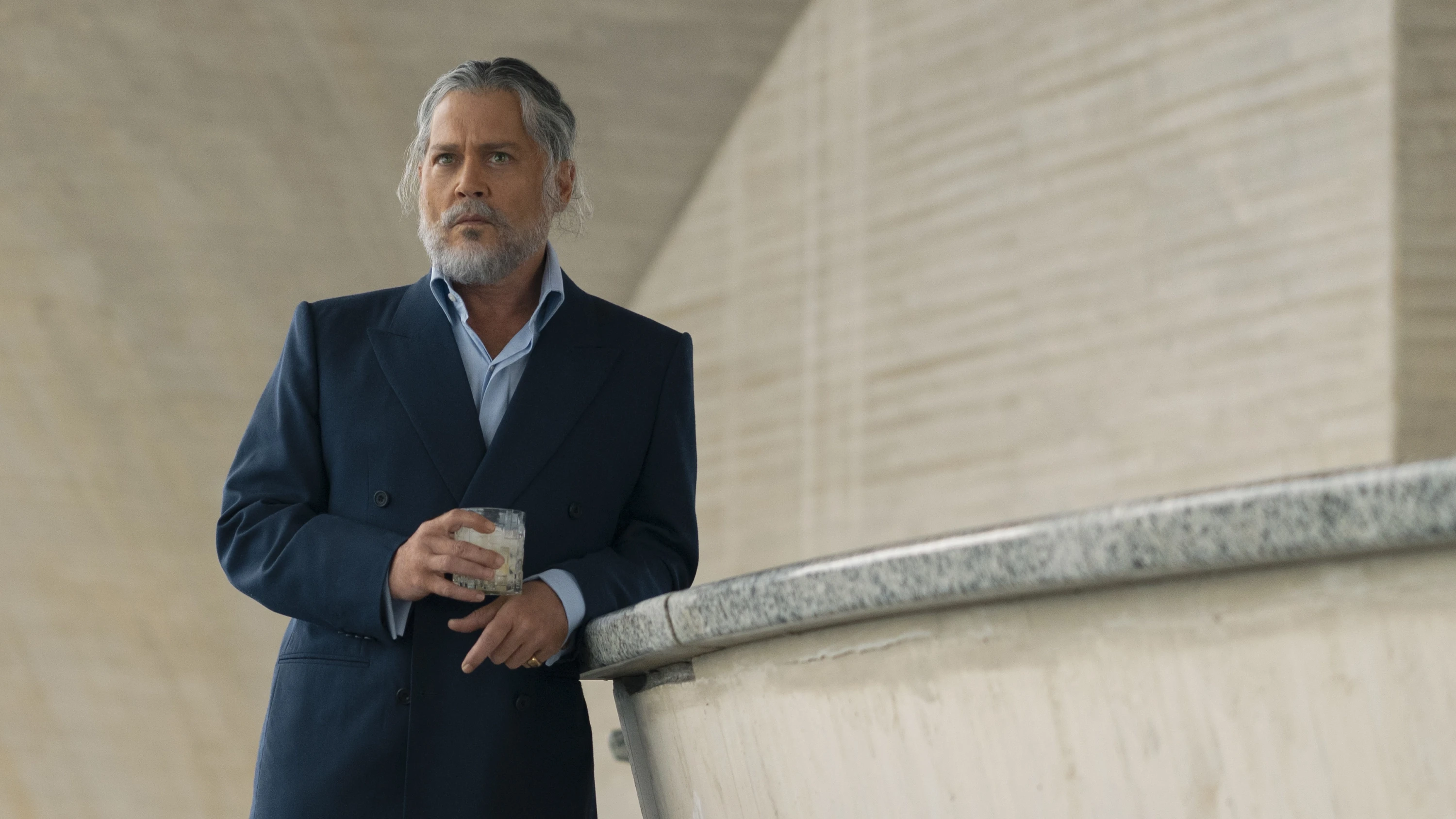 Johnny Depp, with gray hair and beard, holds a drink in an official Day Drinker film still.
