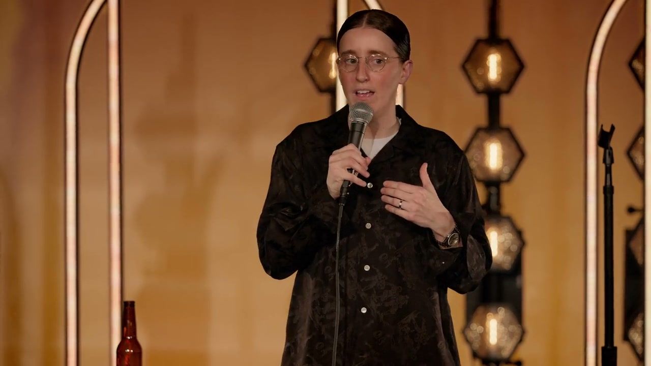 Robby Hoffman speaks with her hand against her chest in front of gold arches in Wake Up.