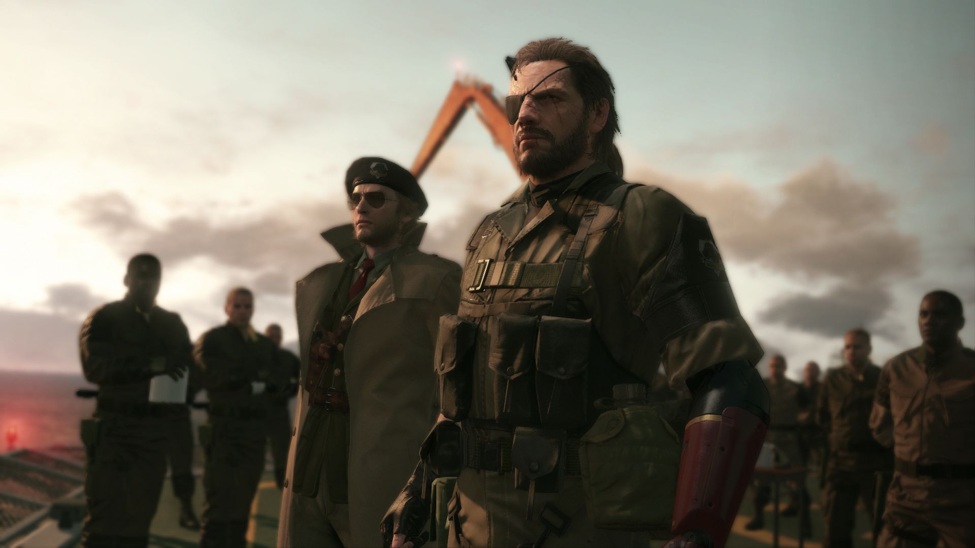 Snake stands with other soldiers in a dusty outdoor scene.