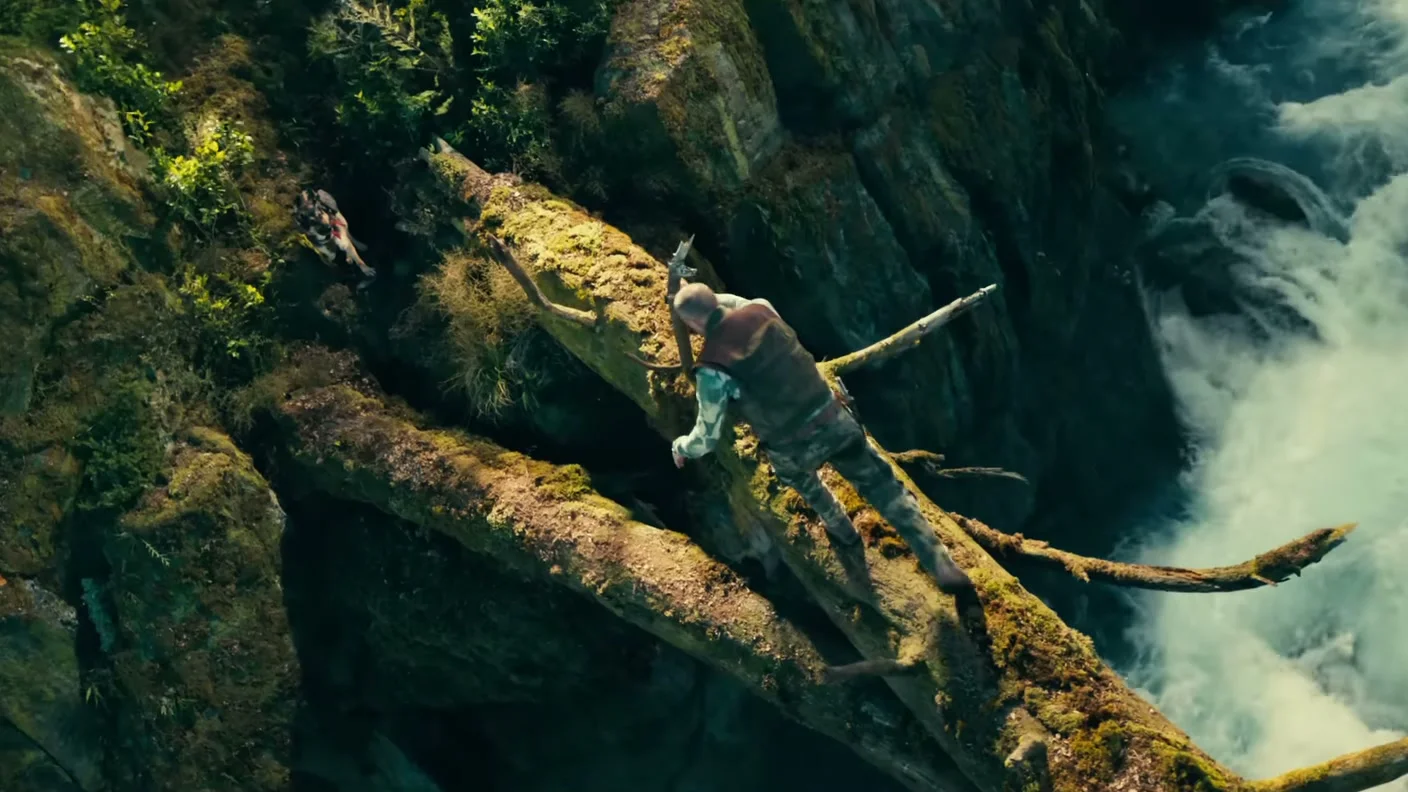 James Belmont and Odin cross a rushing river on a fallen tree in Heart of the Beast.