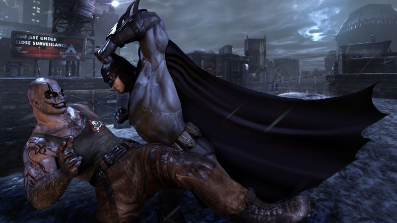 Batman holds an opponent in a close-range takedown with city buildings behind them.
