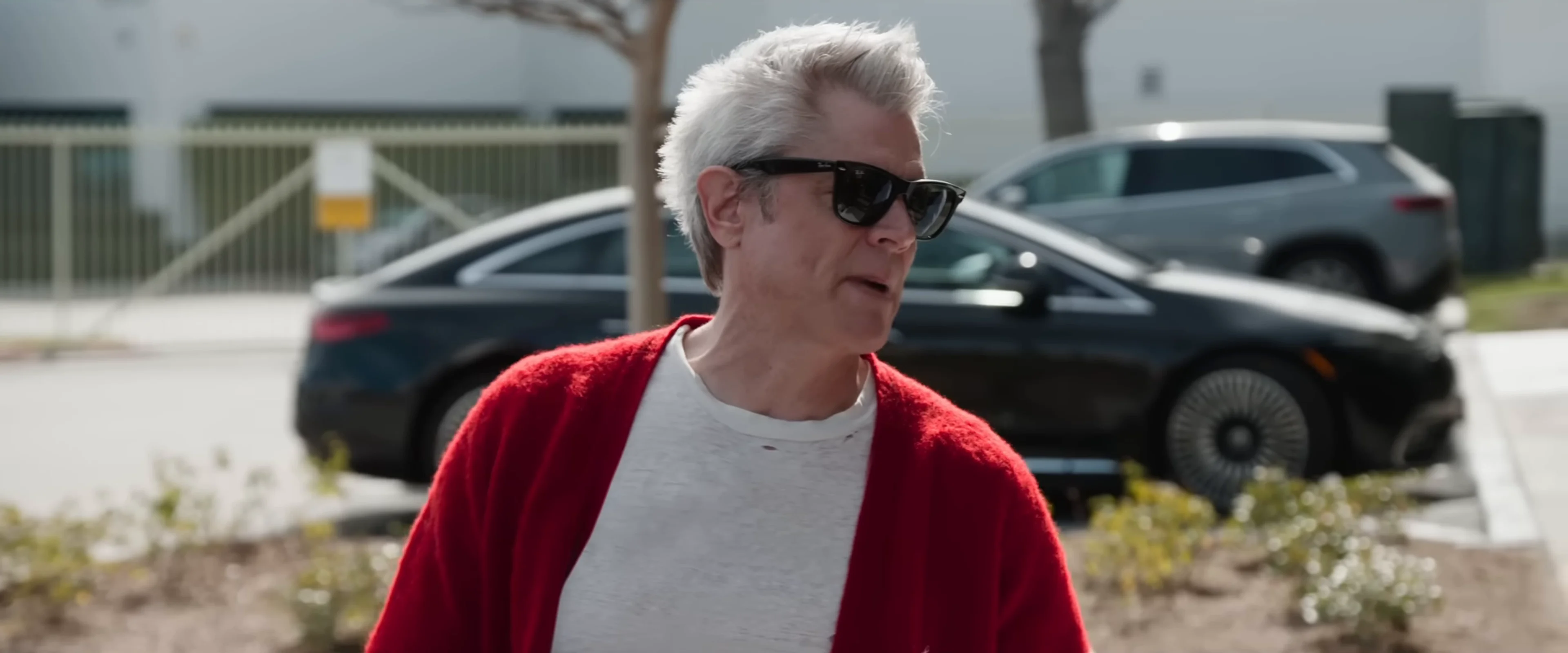 Johnny Knoxville stands outdoors in a red cardigan in the official Best and Last trailer.