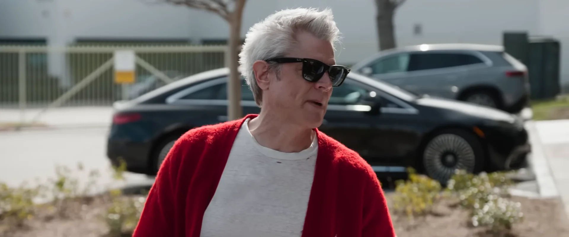 Johnny Knoxville stands outdoors in a red cardigan in the official Best and Last trailer.