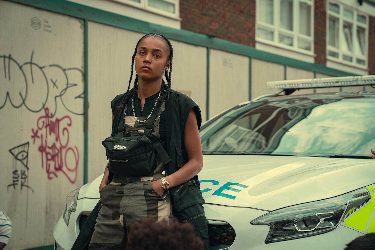 Jasmine Jobson as Jaq stands beside a police car in Top Boy.