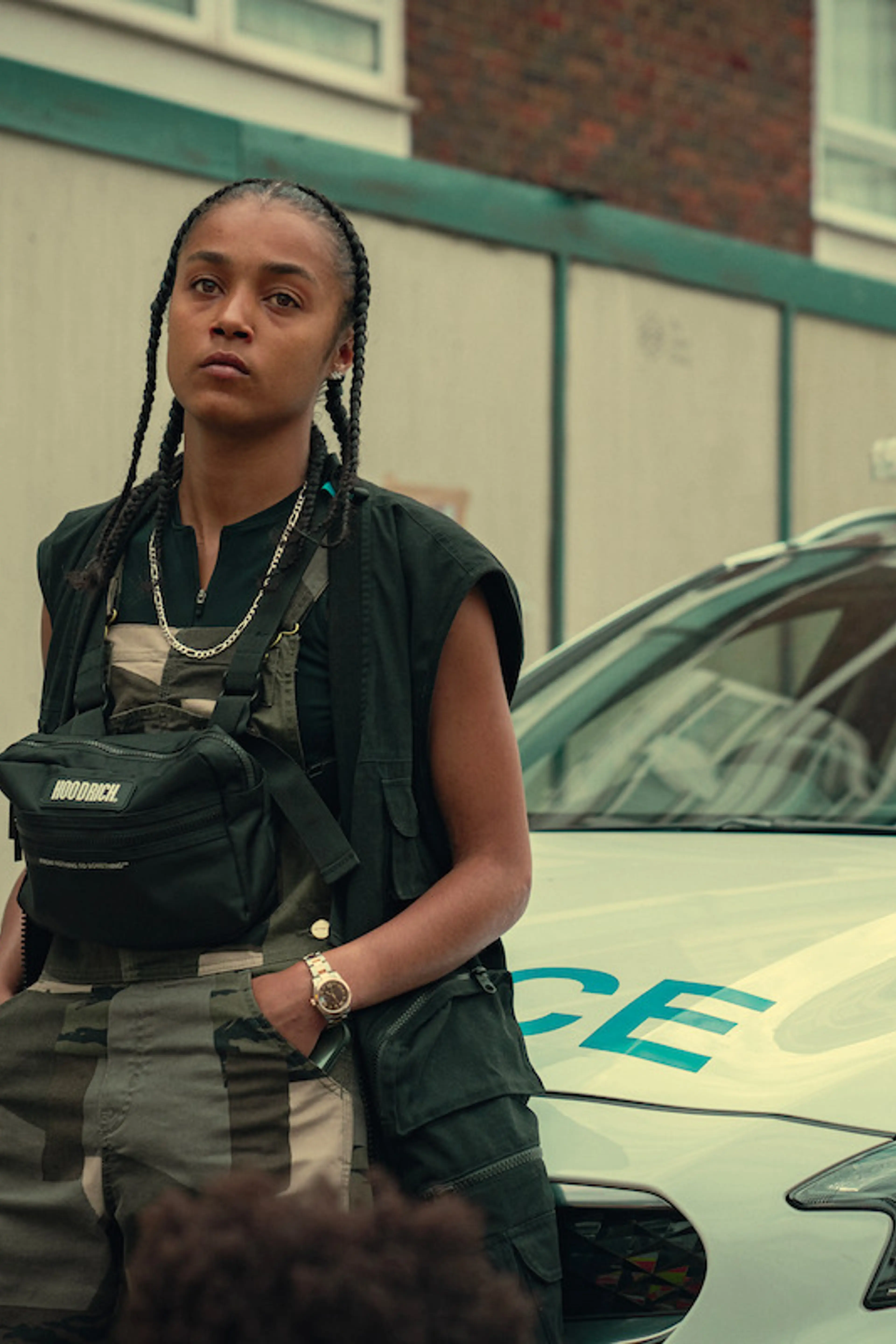 Jasmine Jobson as Jaq stands beside a police car in Top Boy.