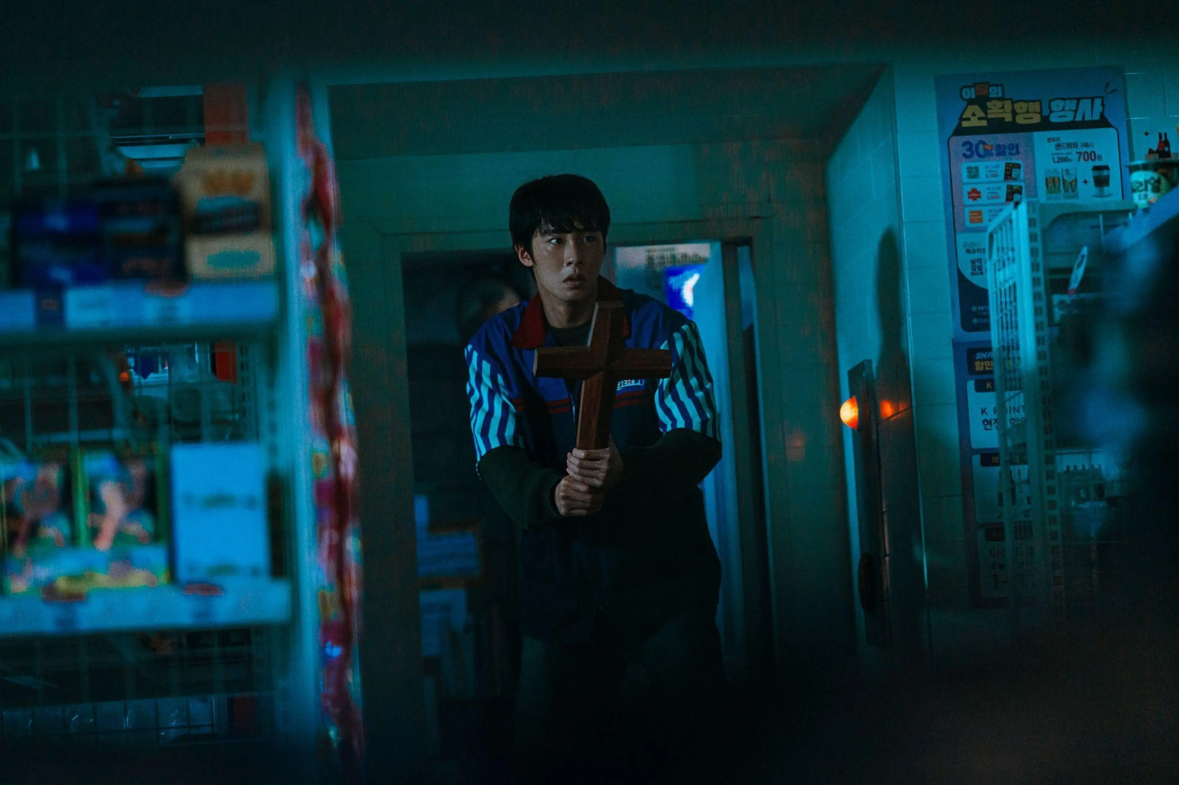 A young man stands in a damaged convenience store.