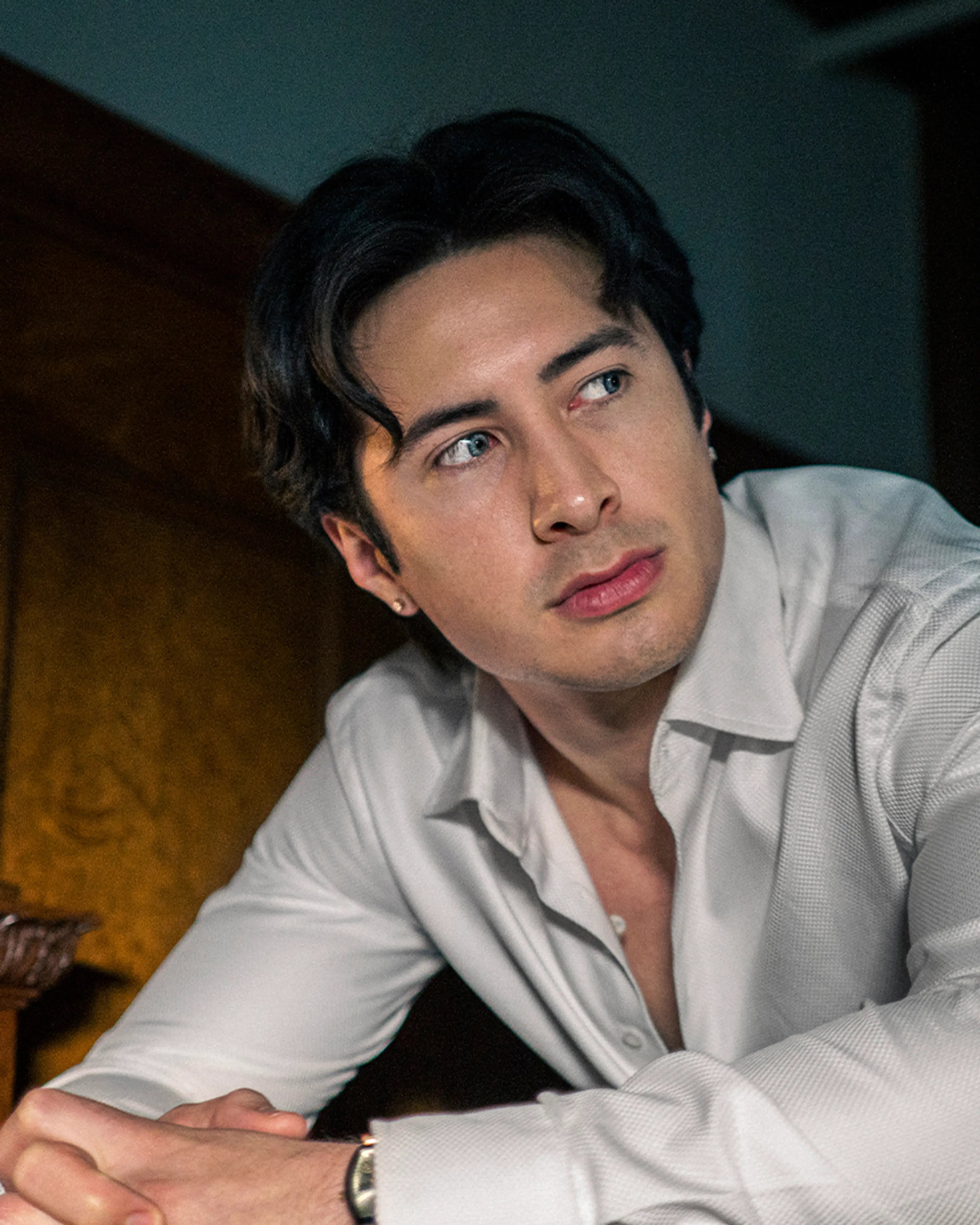 Hudson Williams as Henry Park wears an open white shirt.