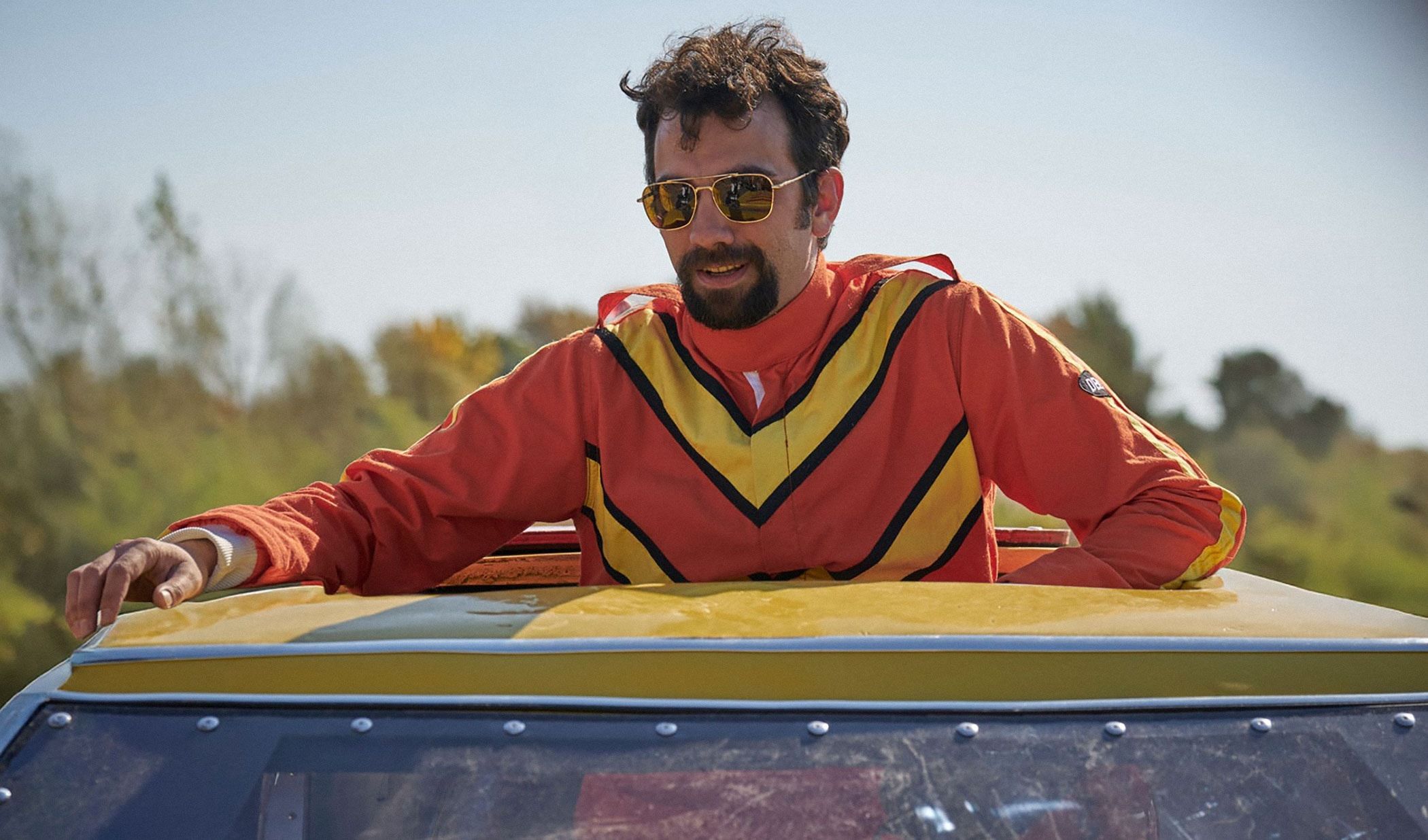 Jay Baruchel as Ken Carter leans on the yellow stunt car.