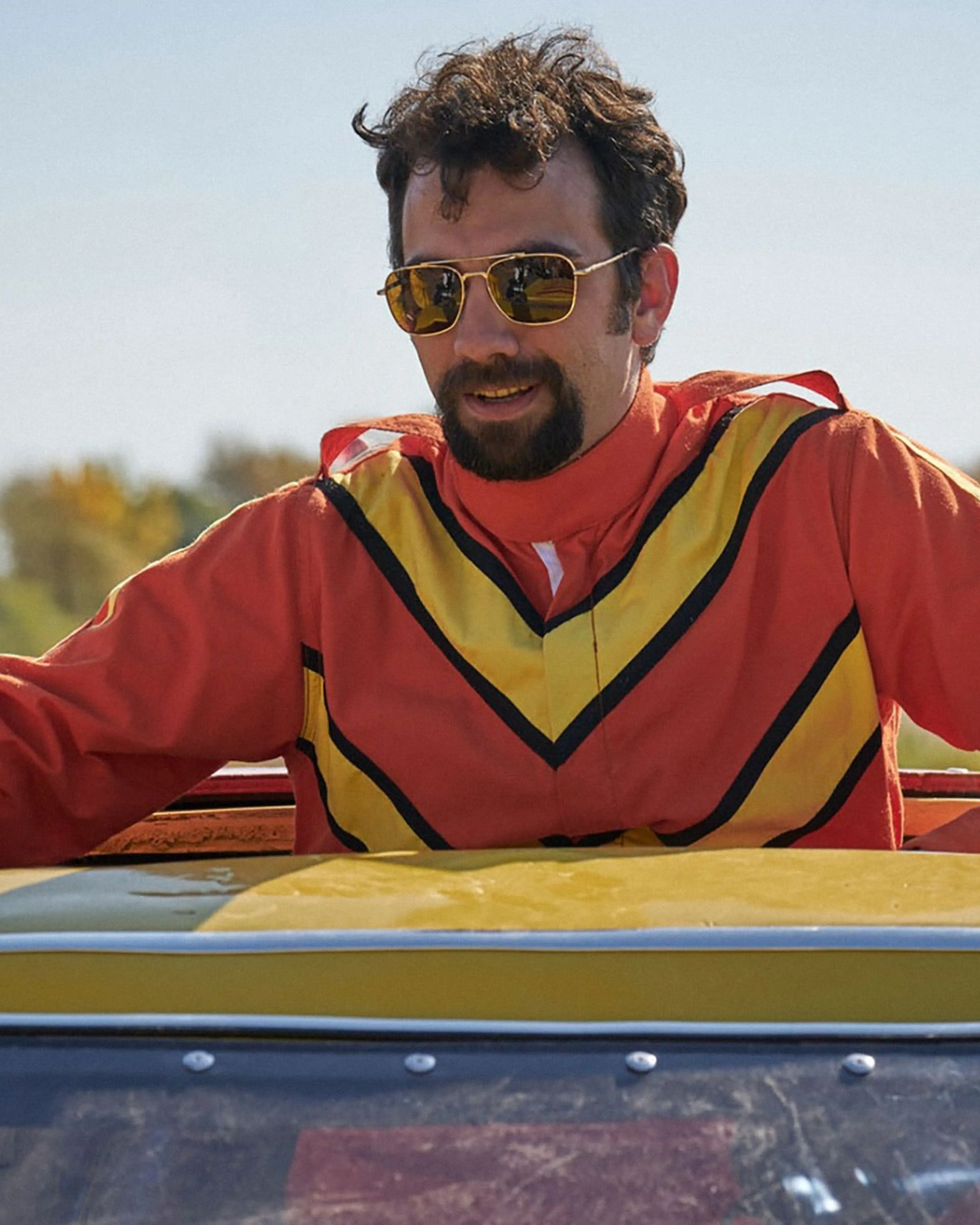 Jay Baruchel as Ken Carter leans on the yellow stunt car.