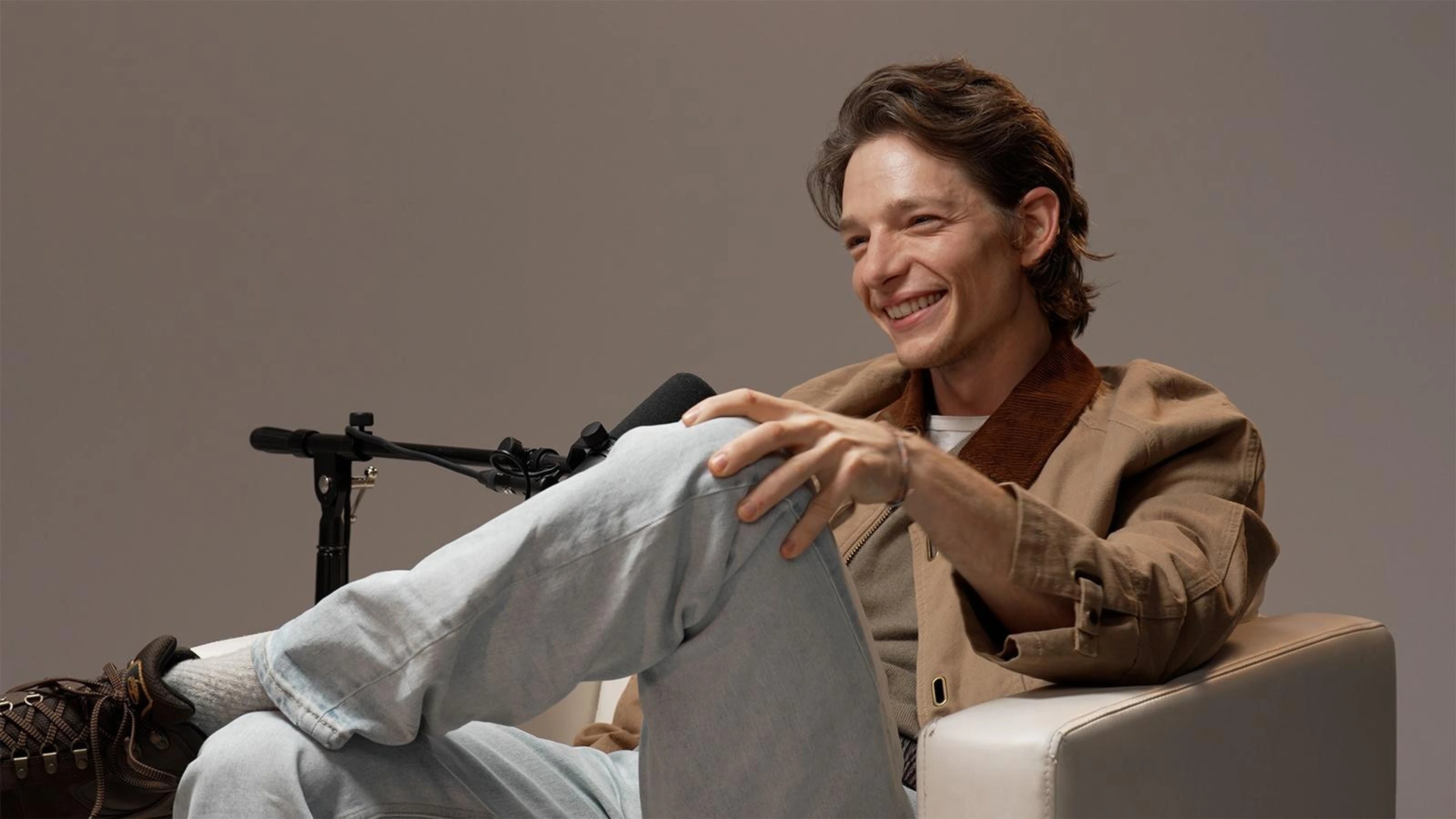 Mike Faist smiles in a brown jacket during his American Masters PBS interview.