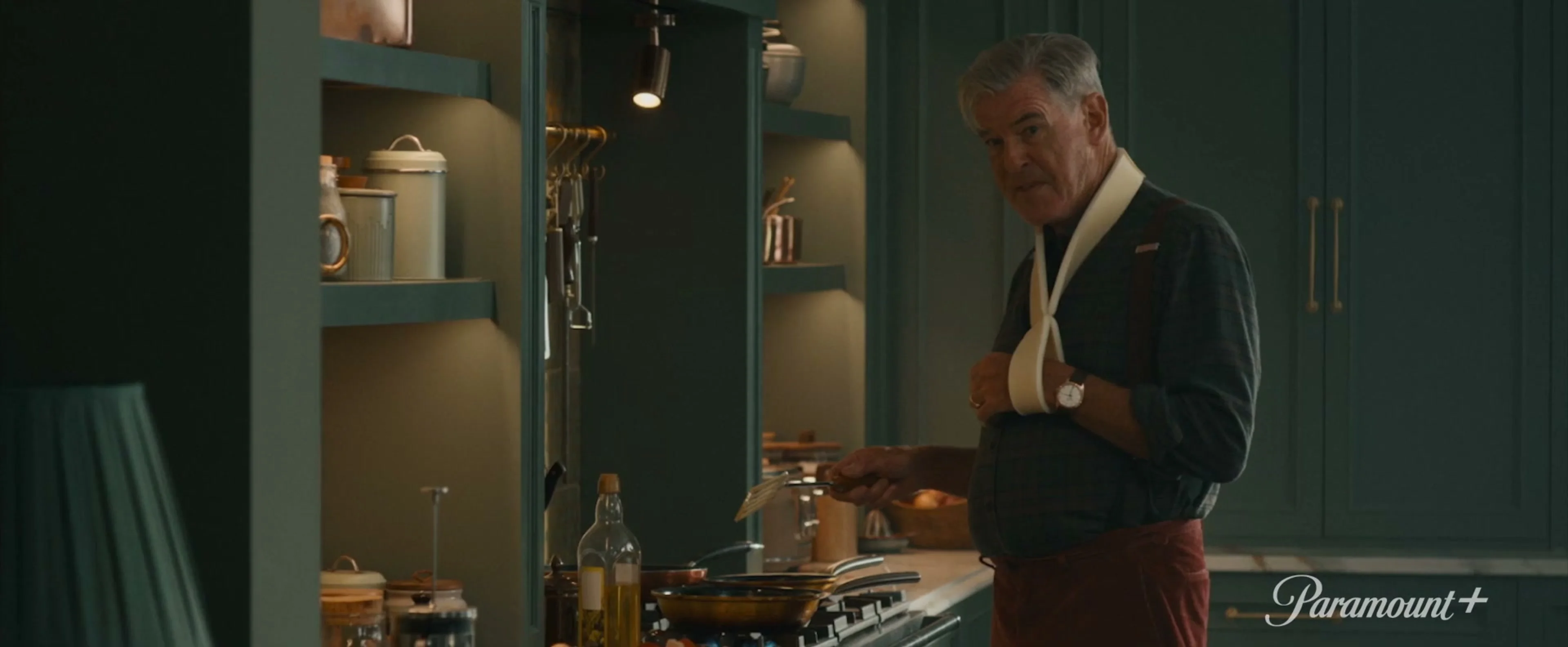 Conrad Harrigan stands in a kitchen with one arm in a sling in MobLand season two.