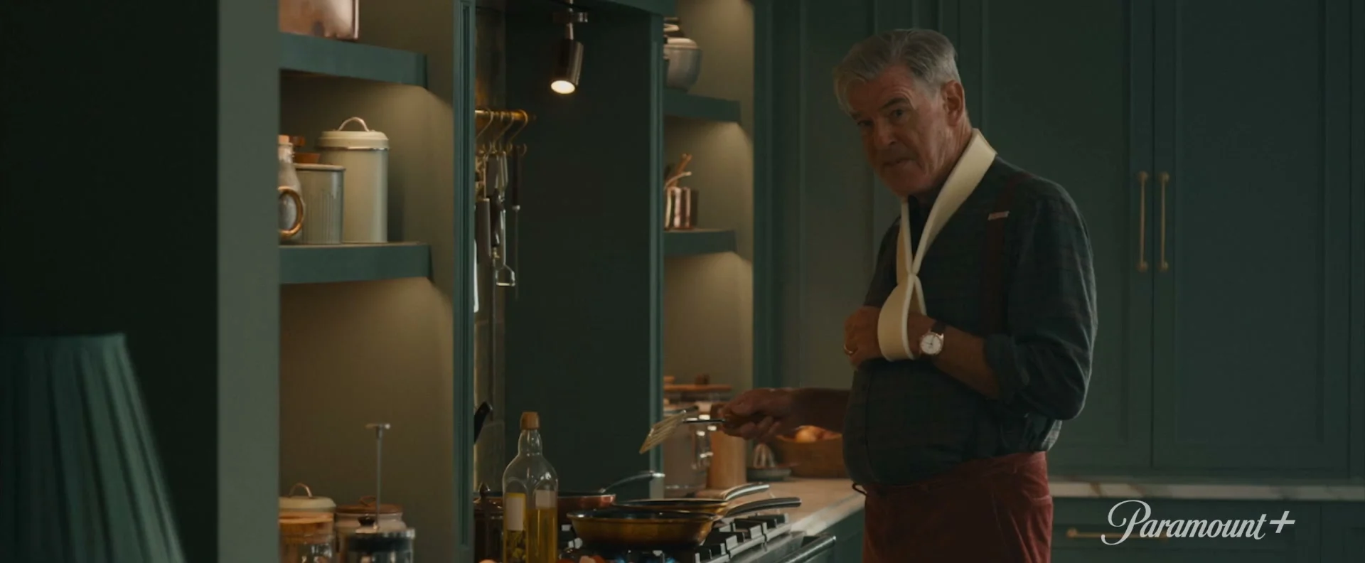 Conrad Harrigan stands in a kitchen with one arm in a sling in MobLand season two.