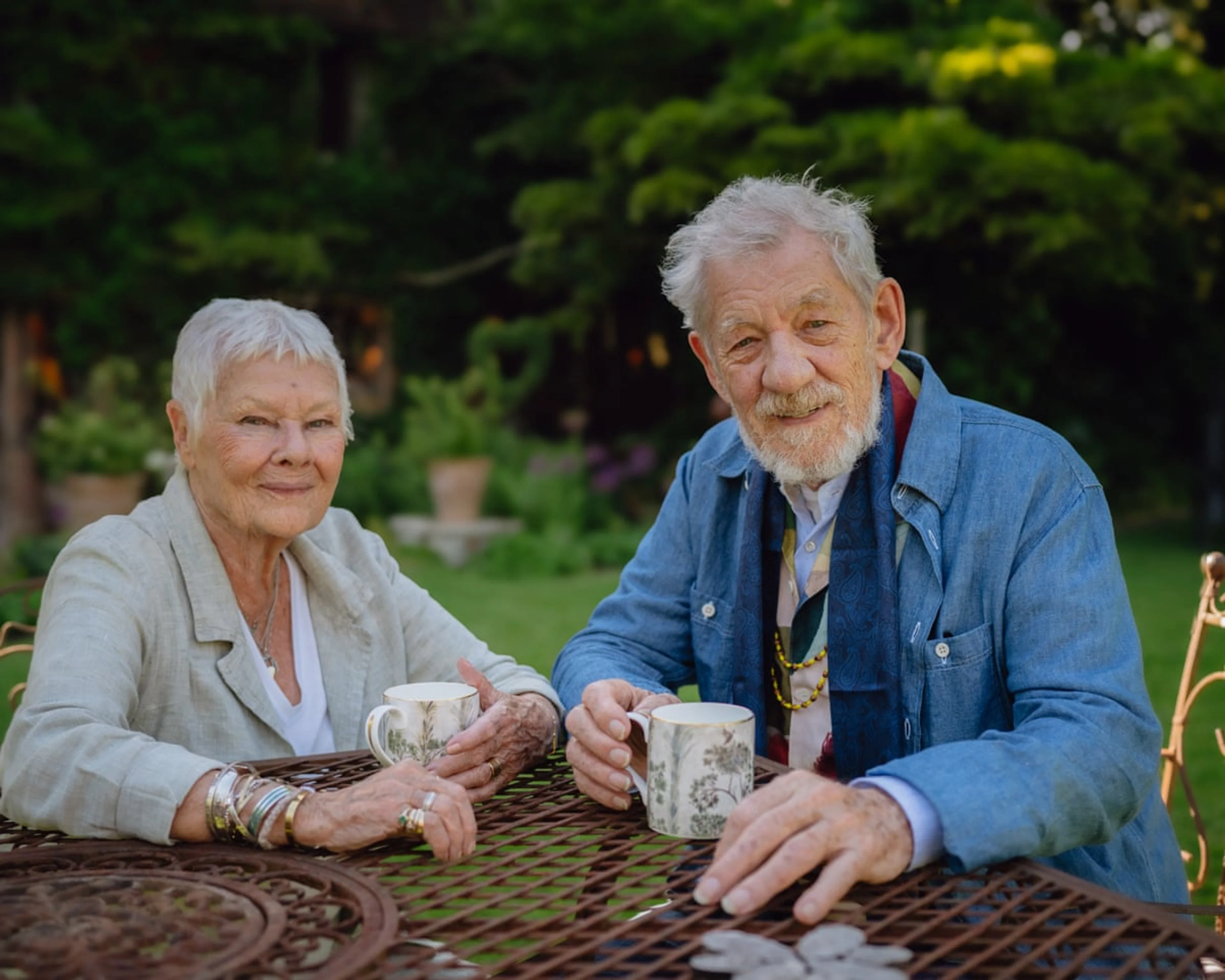 Judi Dench and Ian McKellen sit together with teacups in the garden in an official still from Tea With Judi Dench.