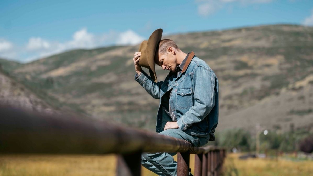 Jefferson White stands beside a ranch fence in costume as Jimmy Hurdstrom.