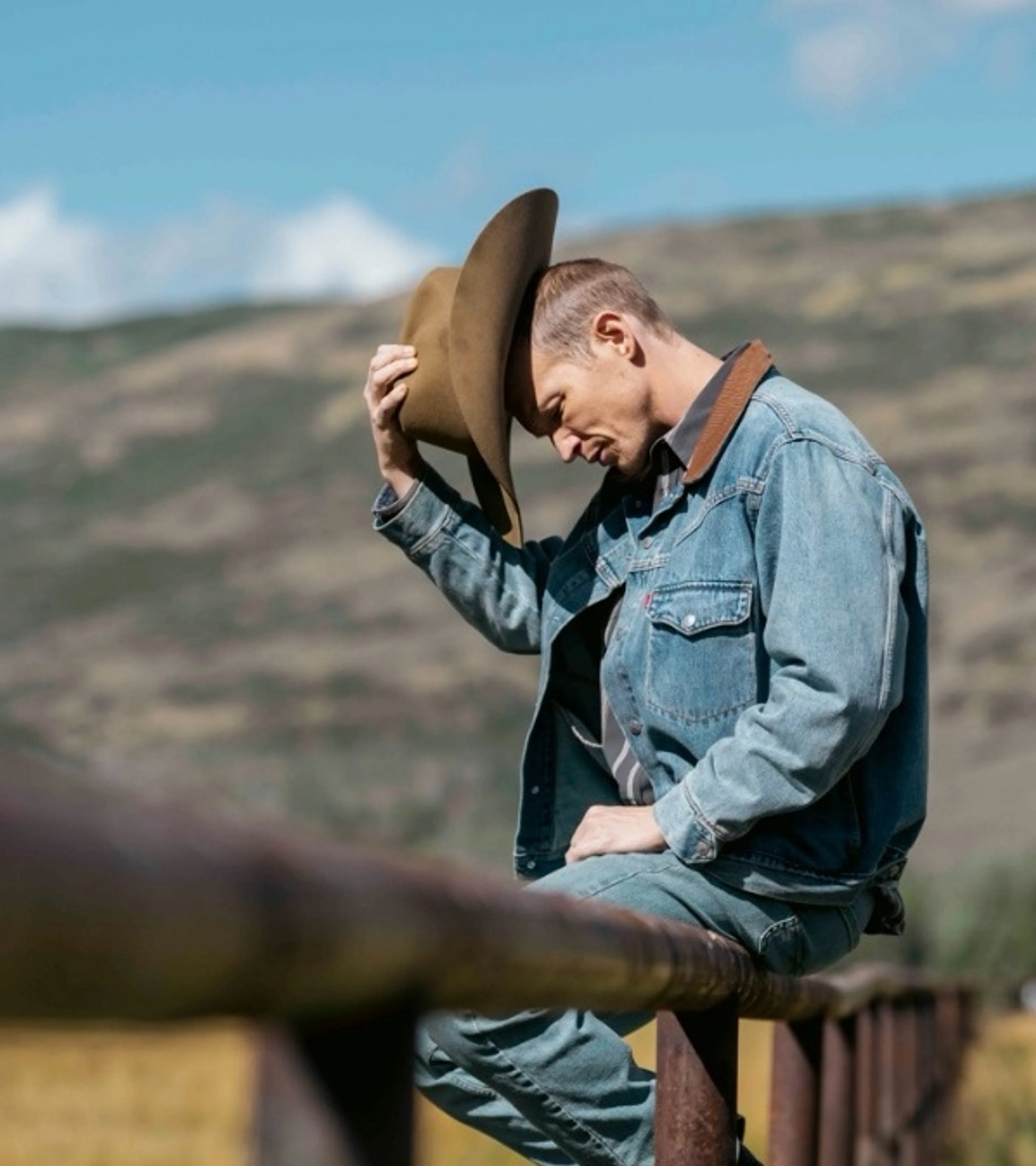 Jefferson White stands beside a ranch fence in costume as Jimmy Hurdstrom.