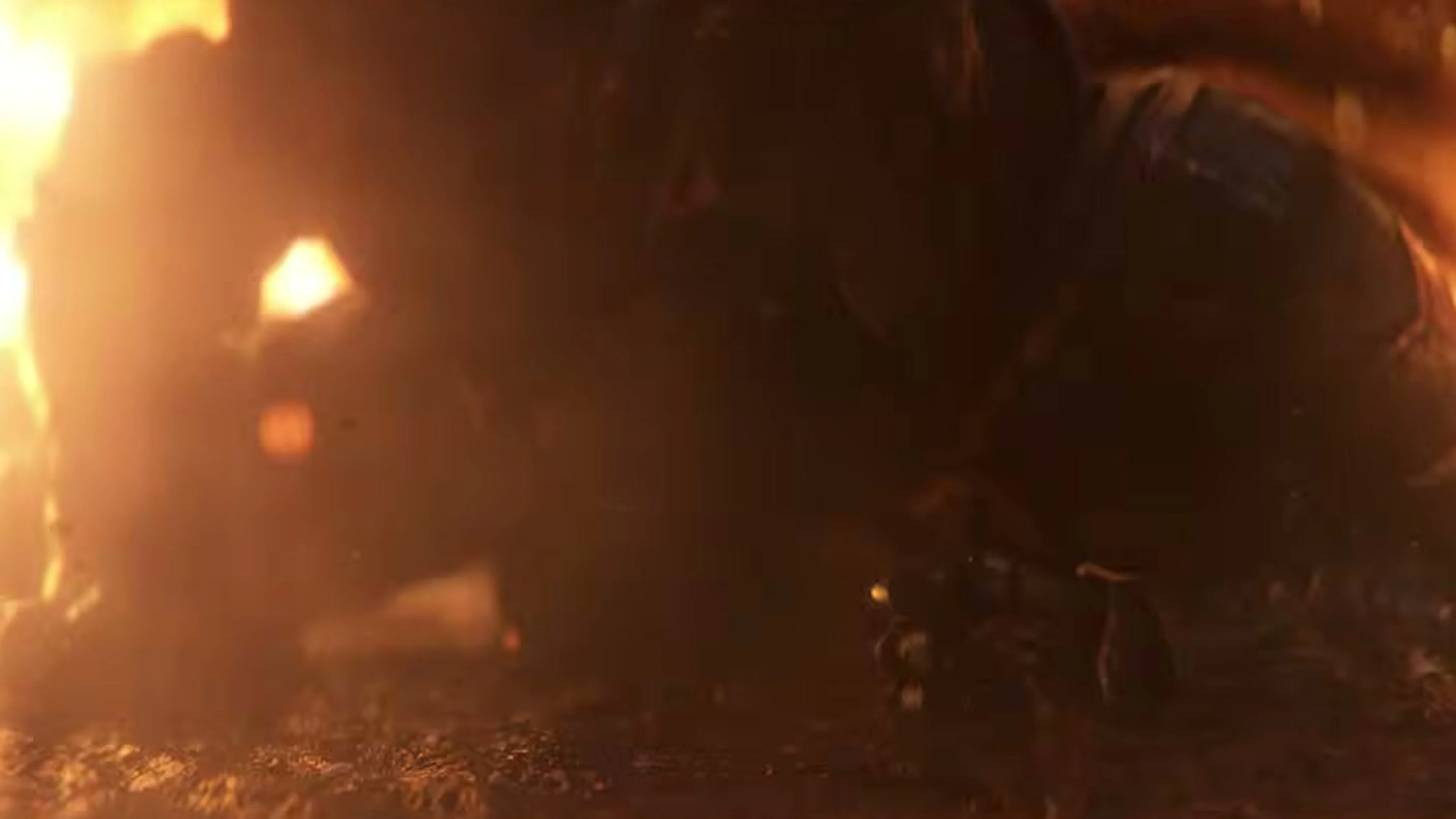 An armored figure kneels on the ground as flames burn behind them.