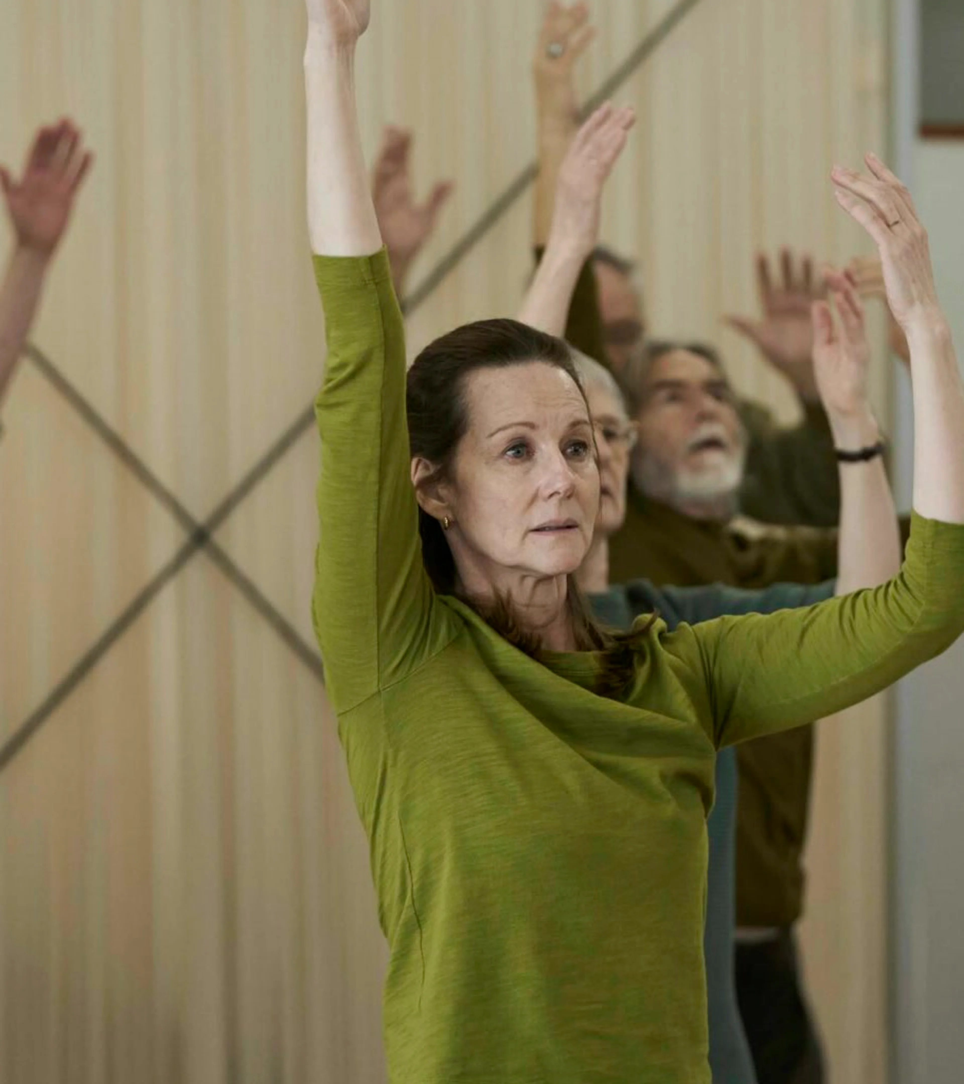 Laura Linney as Emma raises both arms during a movement class in Onwards and Sideways.