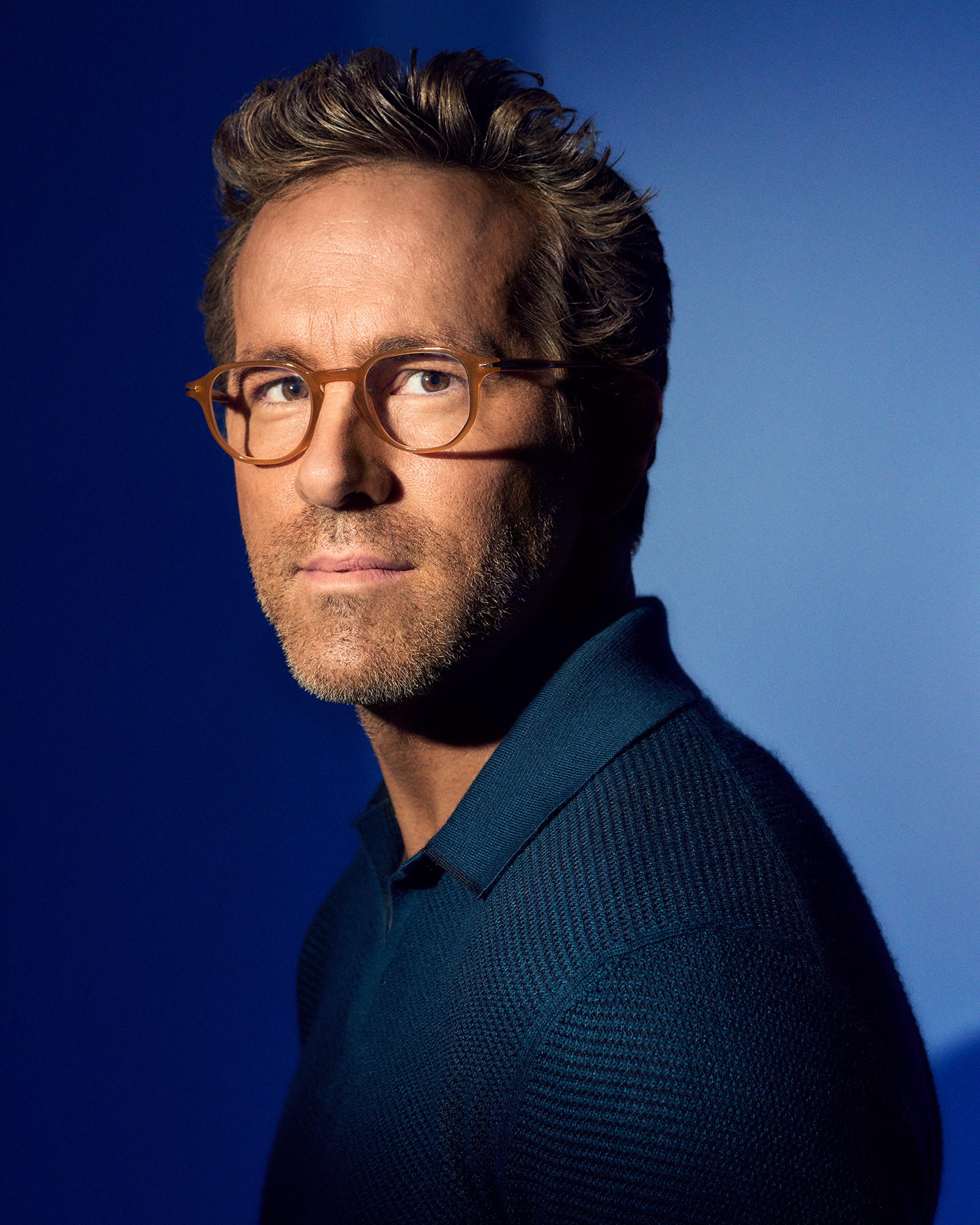 Ryan Reynolds poses in glasses and a dark blue shirt in a TIME portrait.