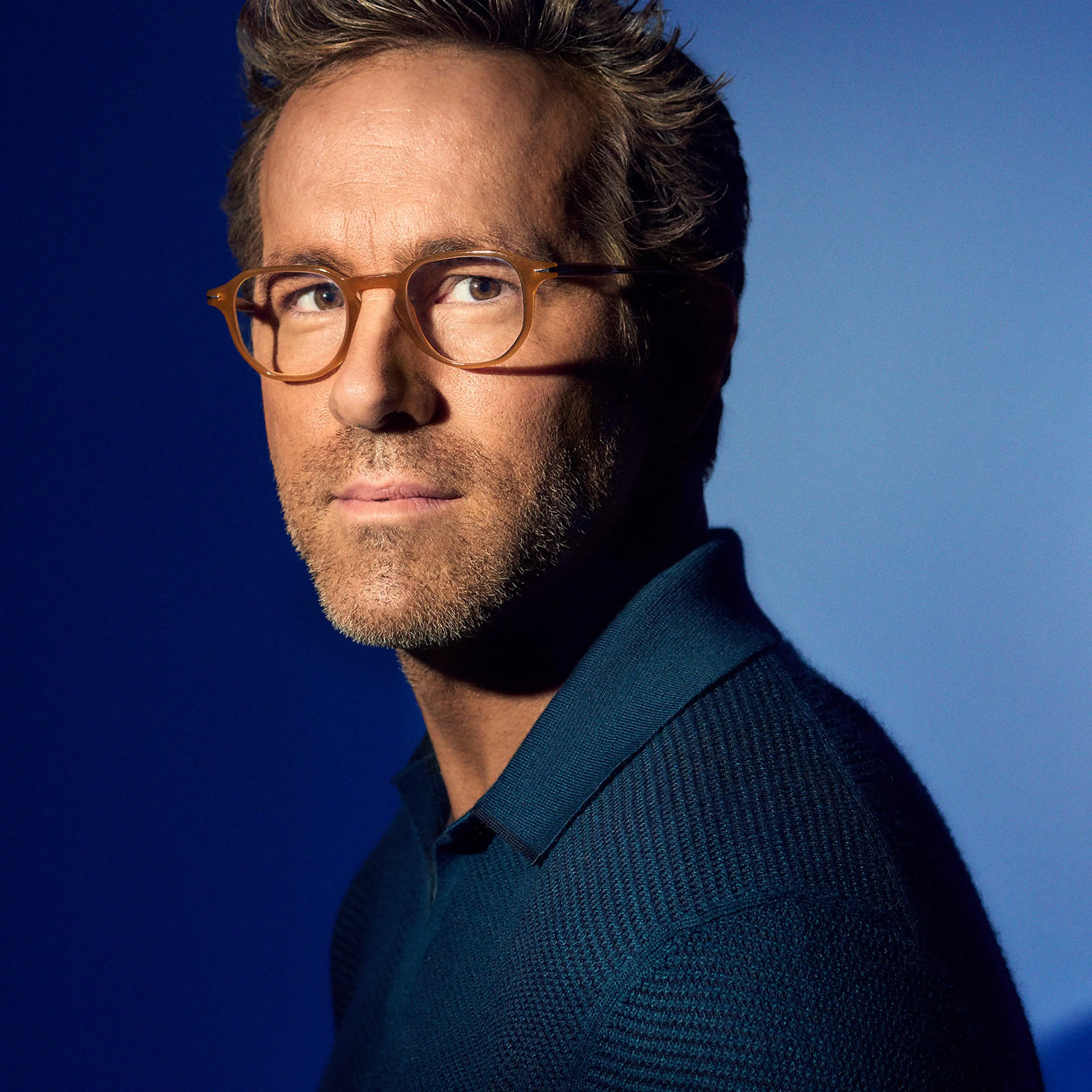 Ryan Reynolds poses in glasses and a dark blue shirt in a TIME portrait.