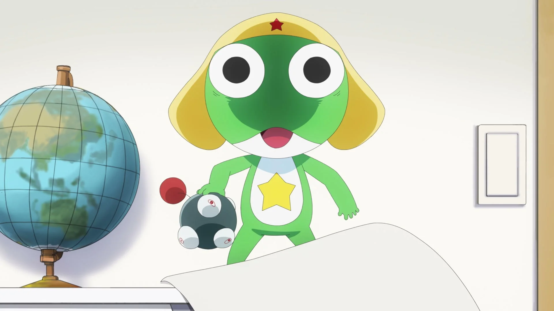 Keroro stands beside a globe and holds a small black device in the new Sgt. Frog anime trailer.