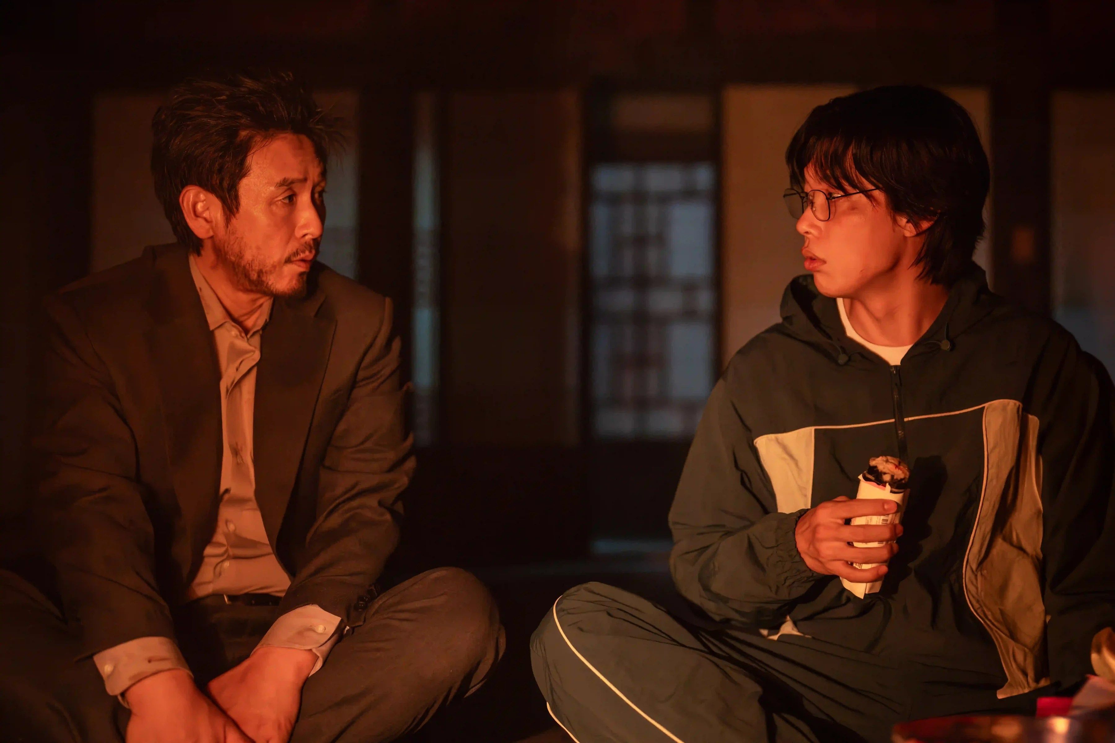 Noja sits beside Moon-jae, who holds a cup and turns to look at him.