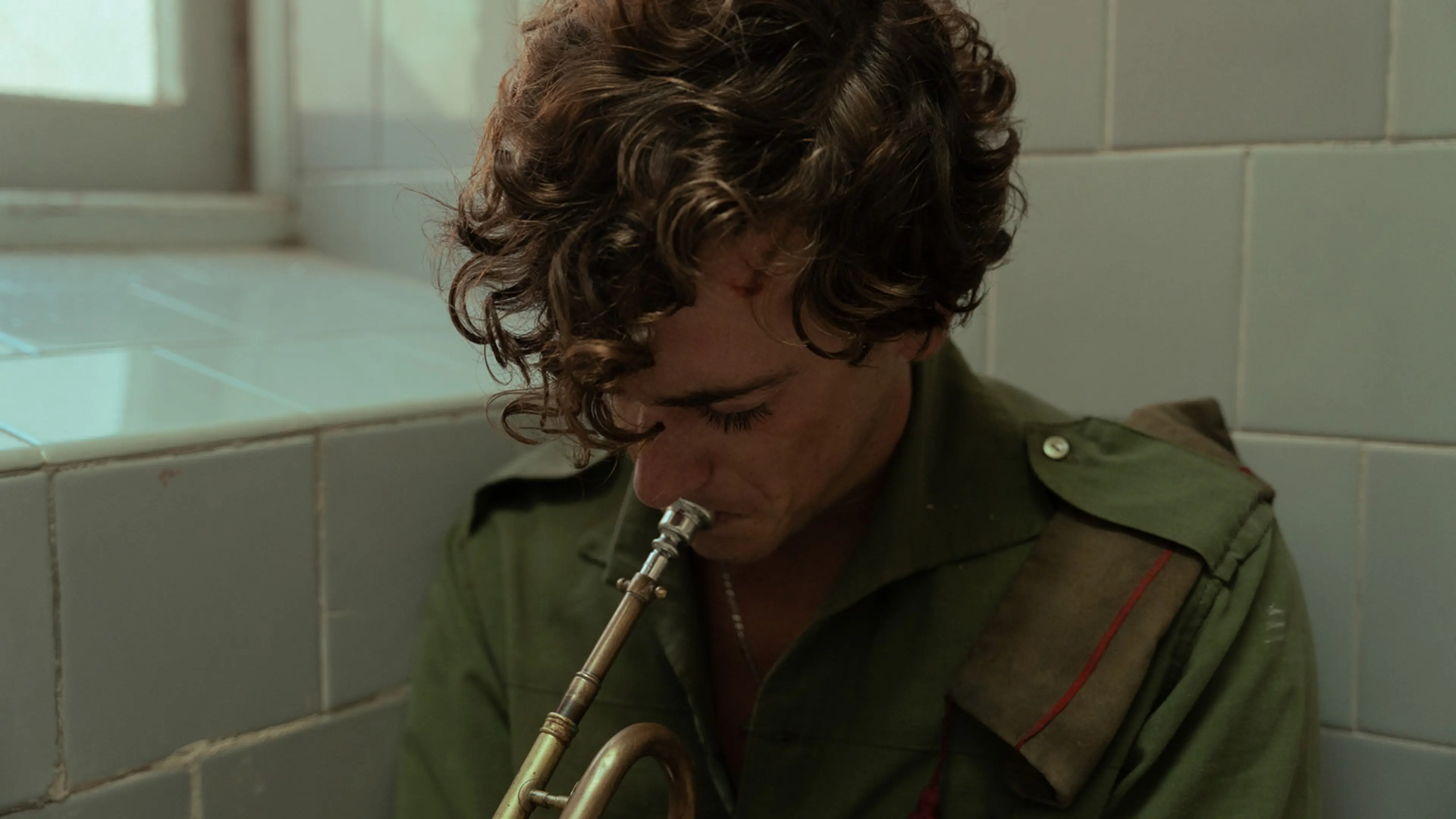 Guitarricadelafuente as Sebastián plays a brass instrument in a tiled room.