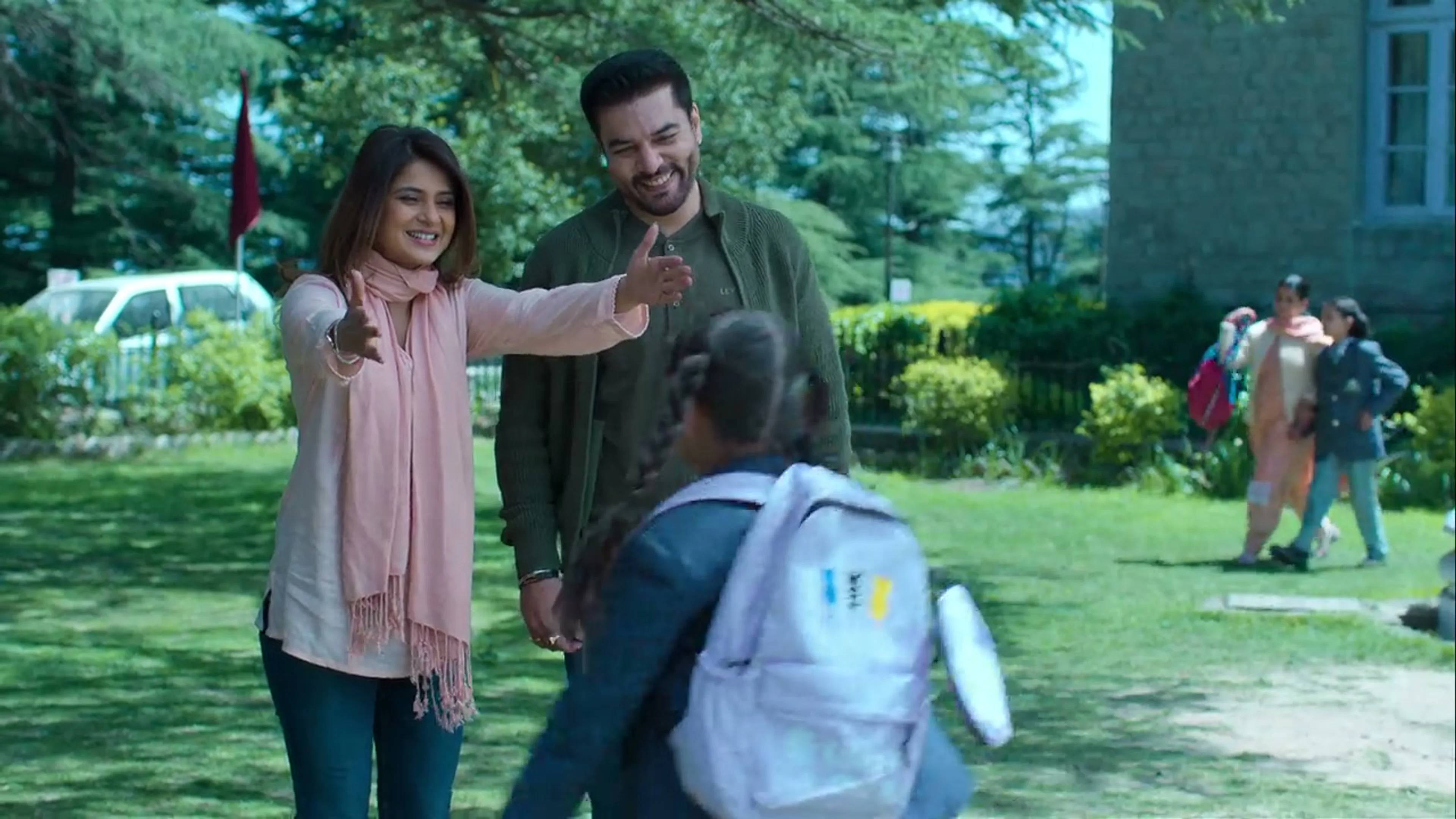 Jennifer Winget as Sakshi opens her arms to Rhea outside school, with Dhruv Chowdhary as Gaurav beside her.