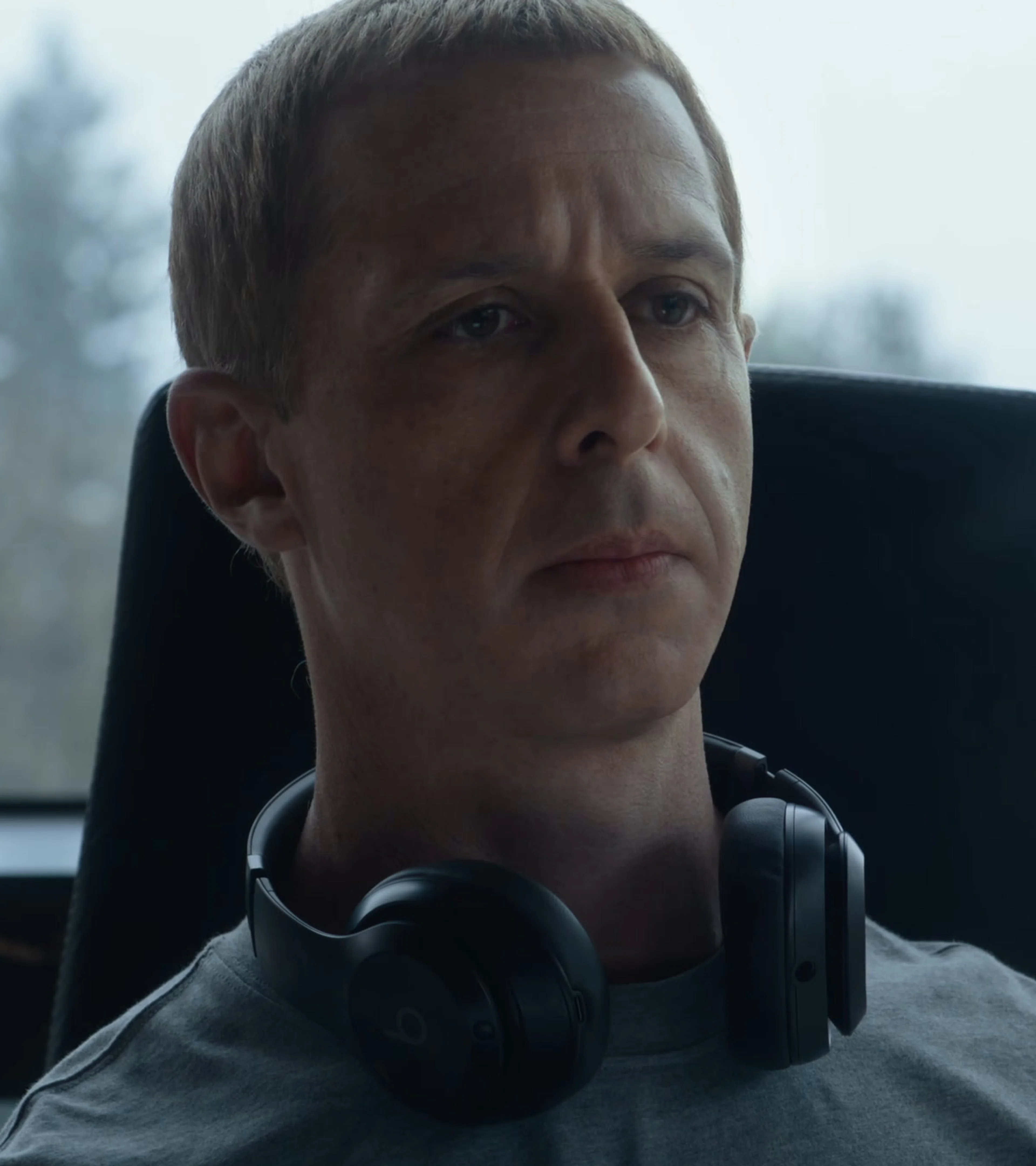 Jeremy Strong as Mark Zuckerberg sits with headphones around his neck in The Social Reckoning.