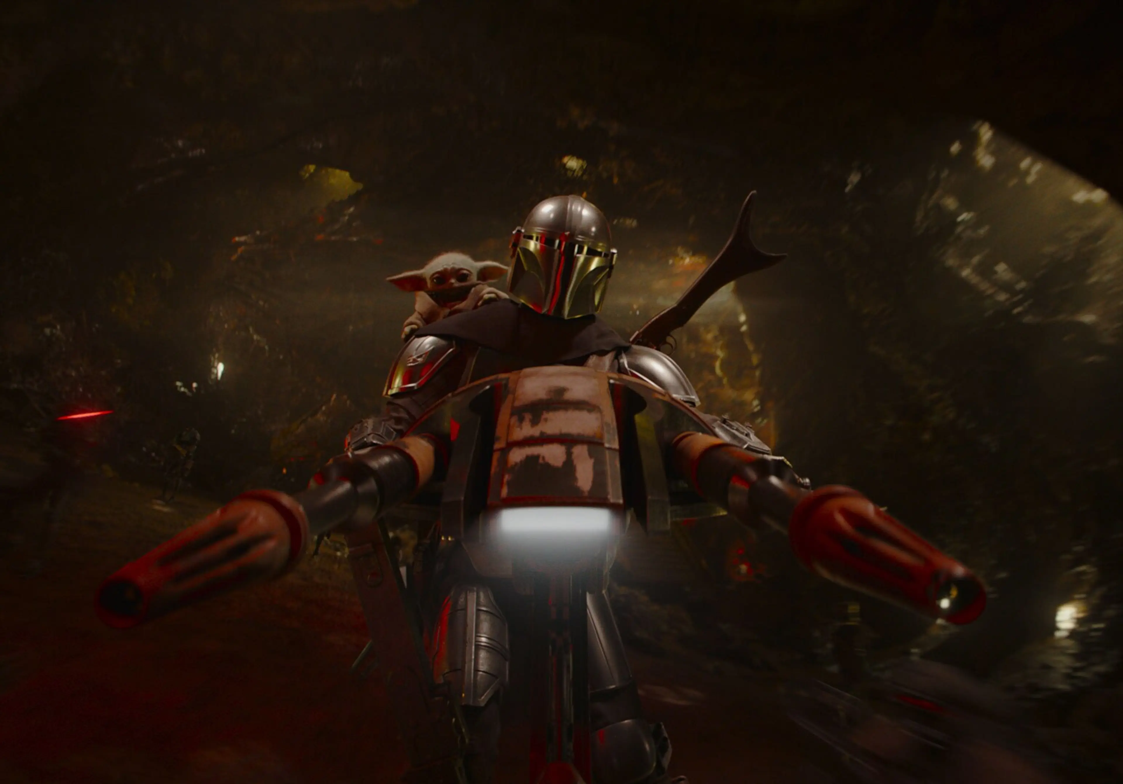 Din drives a speeder through a forest with Grogu behind his shoulder.