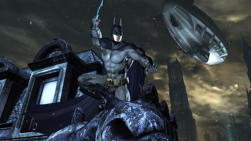 Batman perches high above Gotham with an airship in the sky.