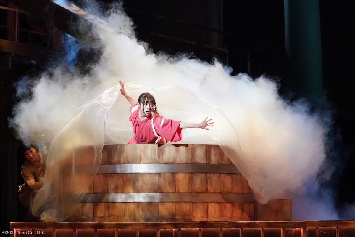 Kanna Hashimoto as Chihiro steps through smoke on the bathhouse set in Spirited Away: Live on Stage.
