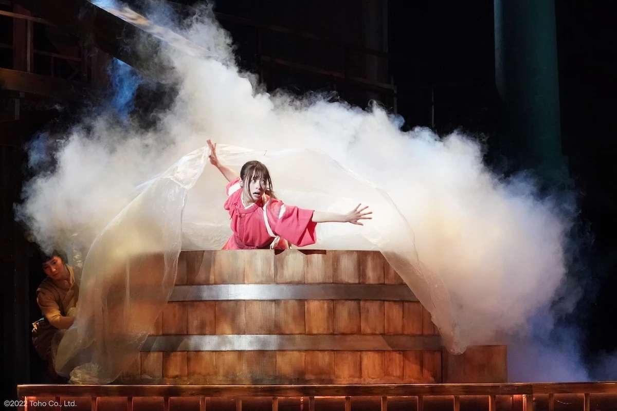 Kanna Hashimoto as Chihiro steps through smoke on the bathhouse set in Spirited Away: Live on Stage.
