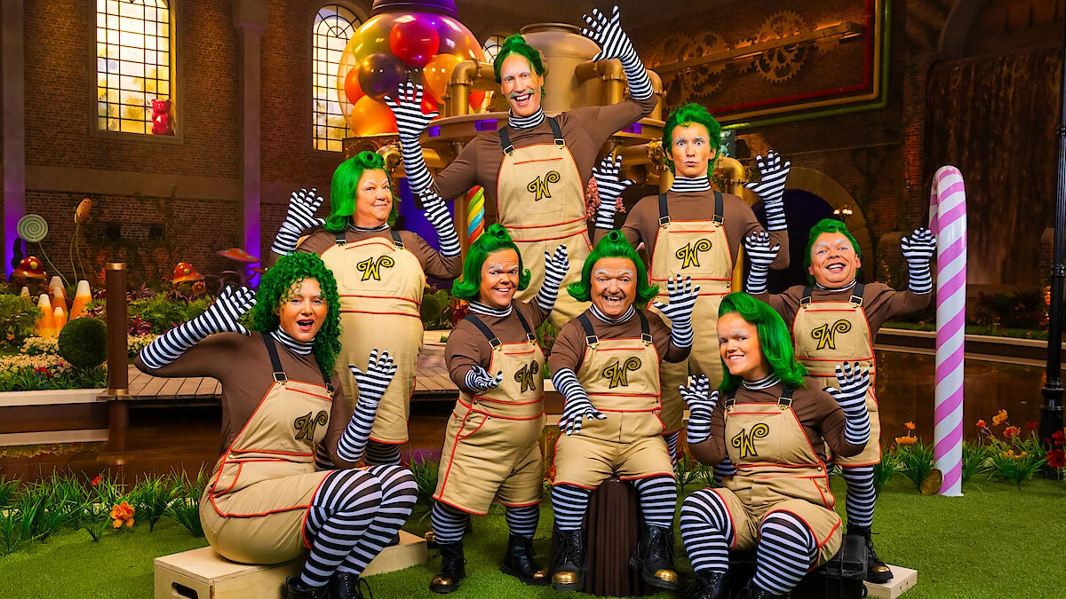 The nine Oompa-Loompa performers from Wonka’s The Golden Ticket stand together on set.