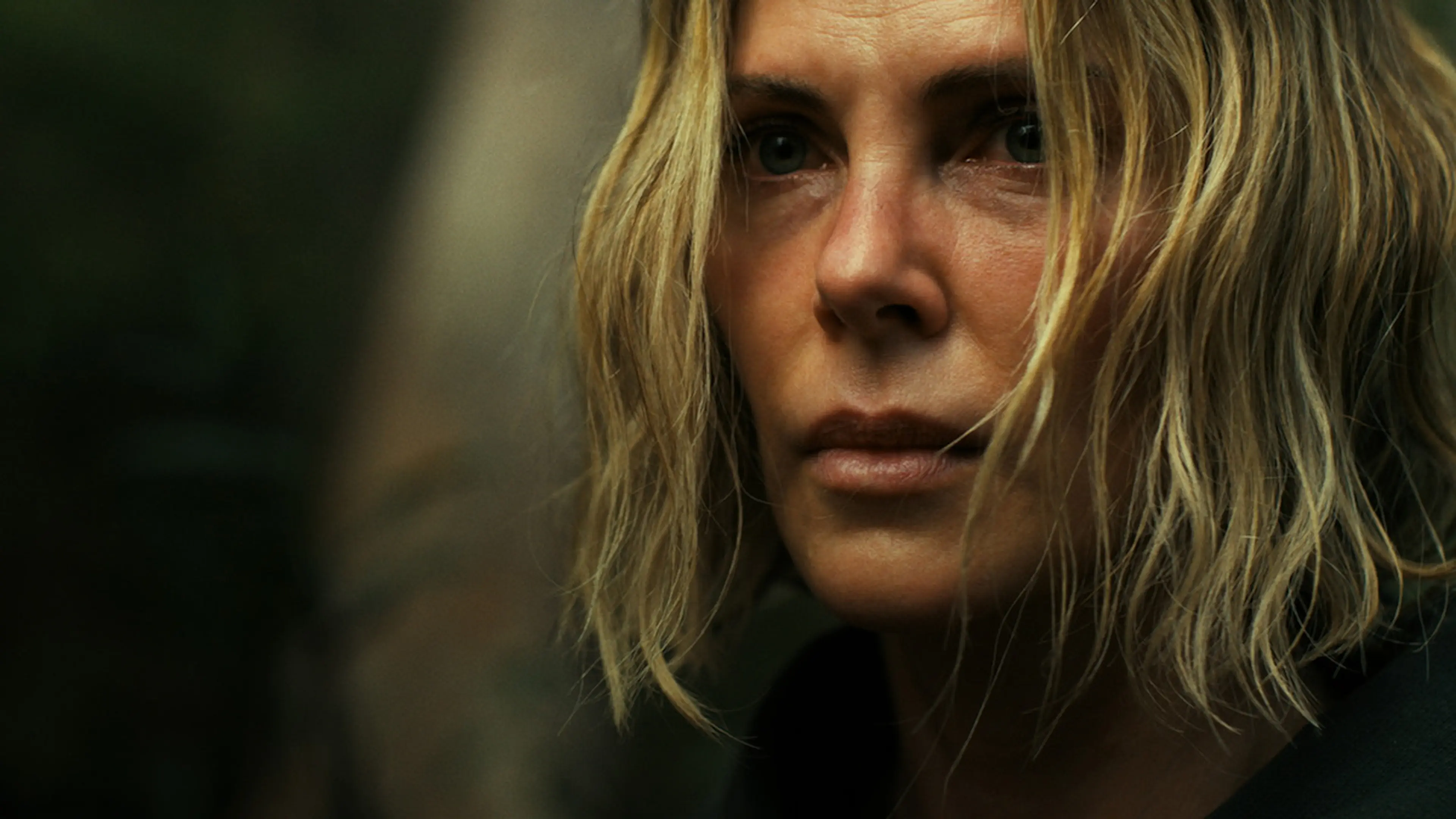 Charlize Theron as Sasha, looking ahead with loose blonde hair around her face.