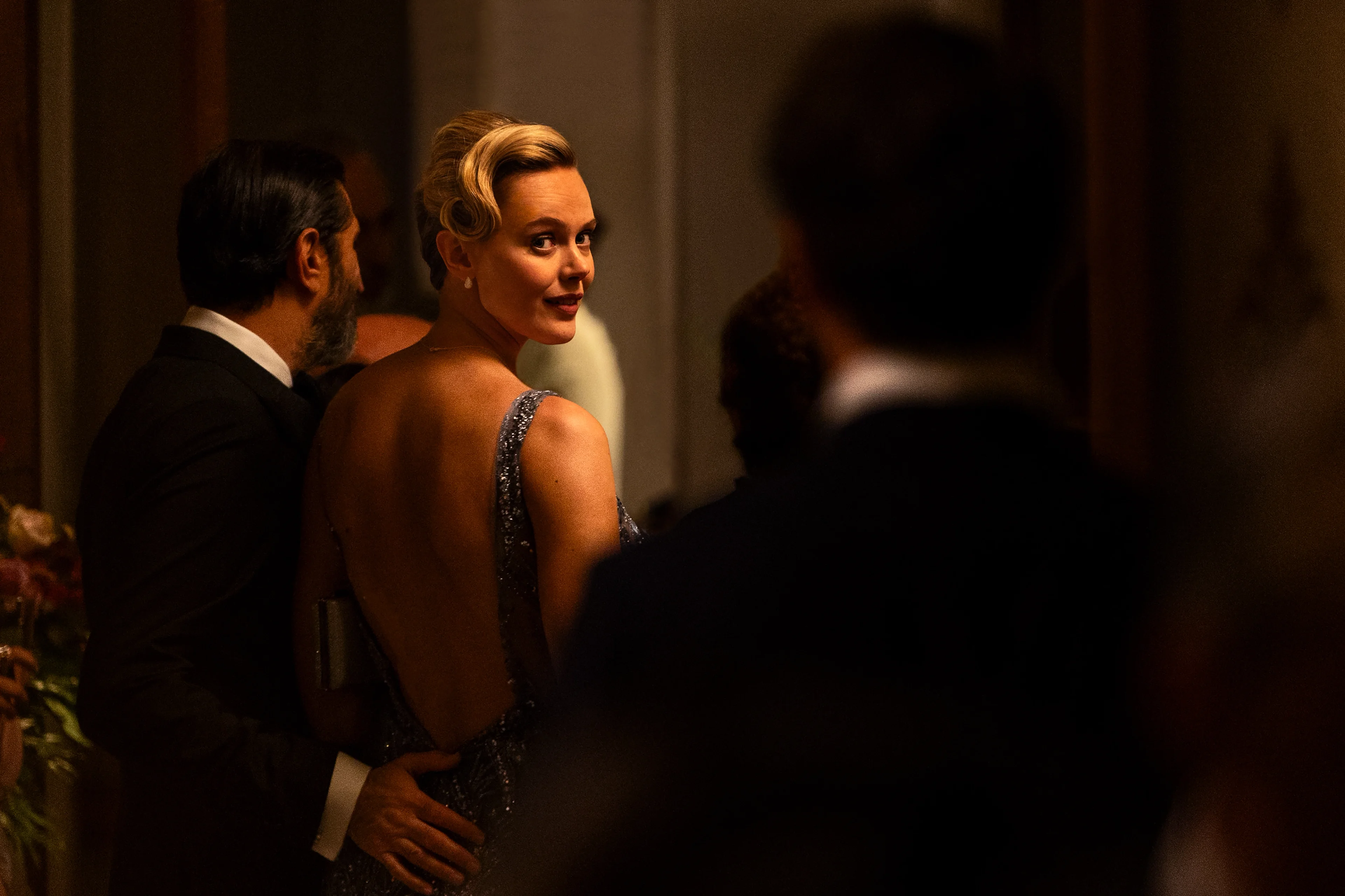 Frida Gustavsson as Helene looks over her shoulder at a formal event.