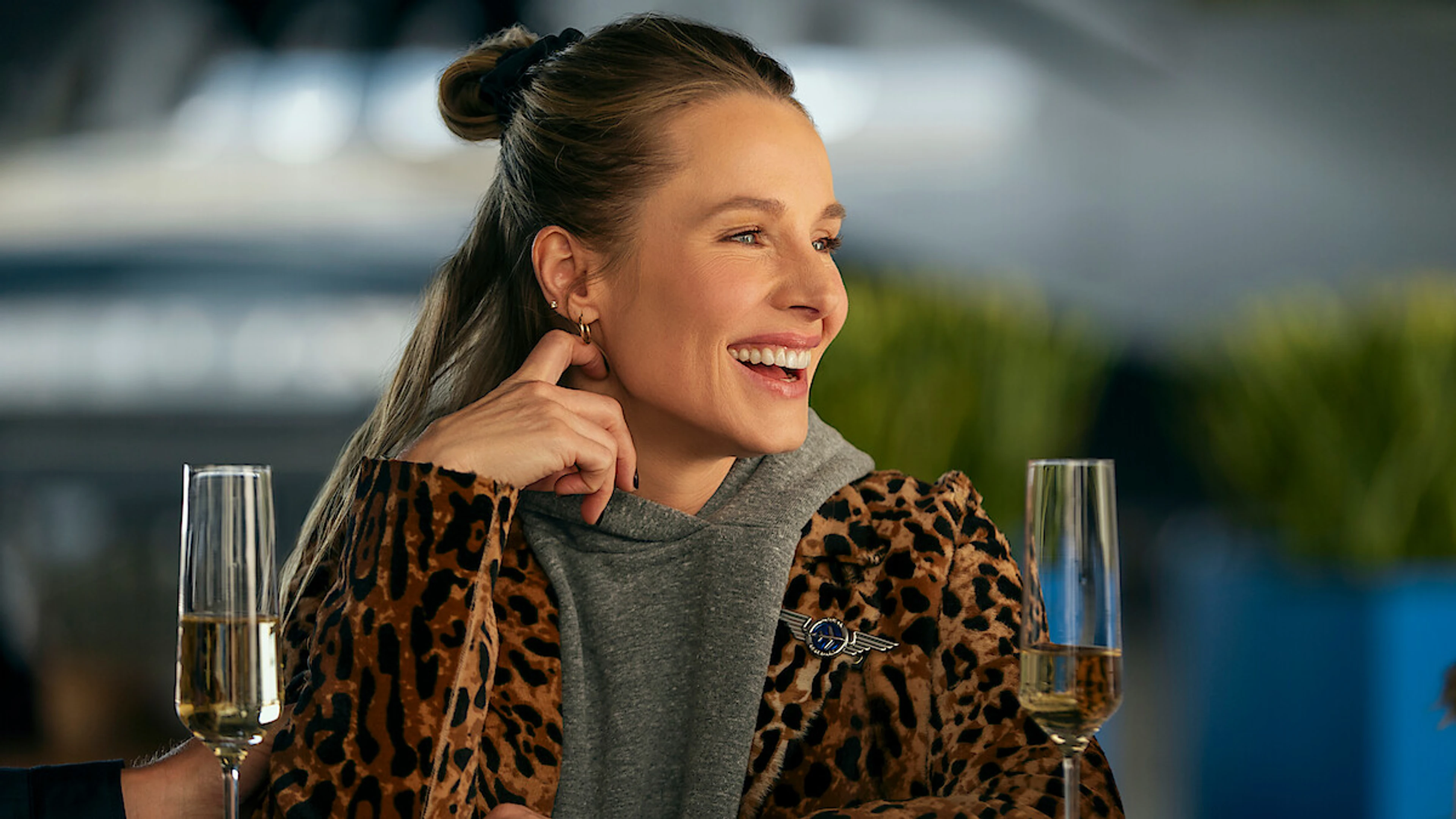 Kristen Bell as Joanne smiles at a table with two champagne glasses in Nobody Wants This Season 3.