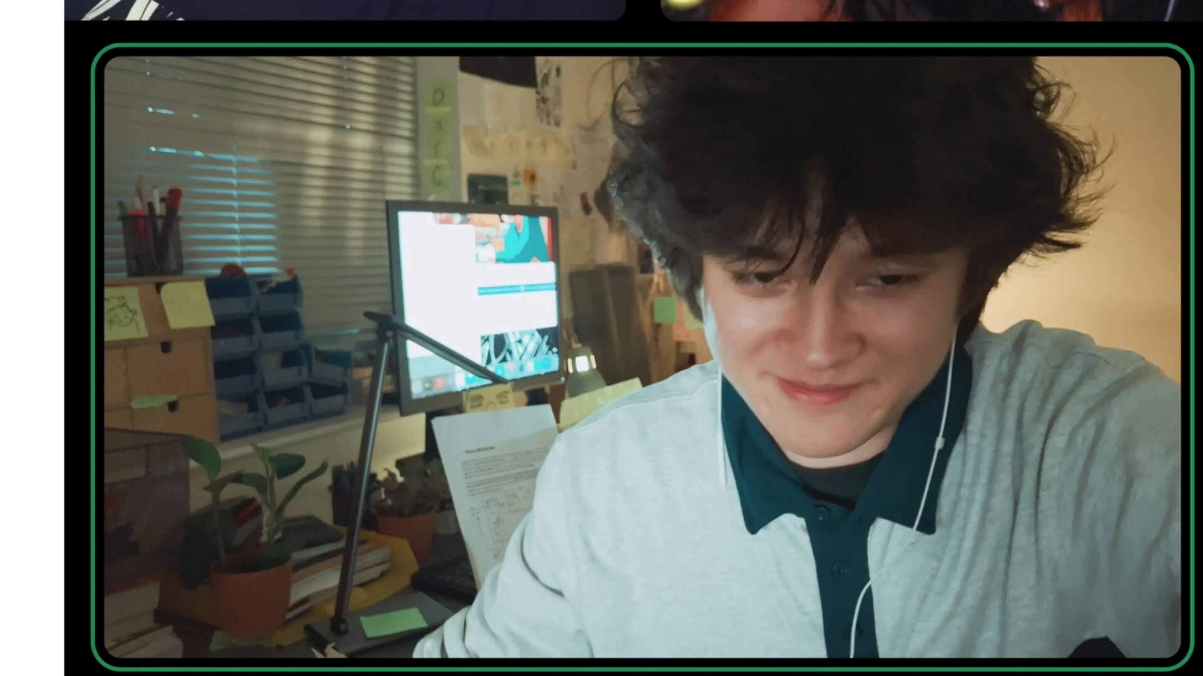Petey smiles during a video call, with notes and furniture behind him.