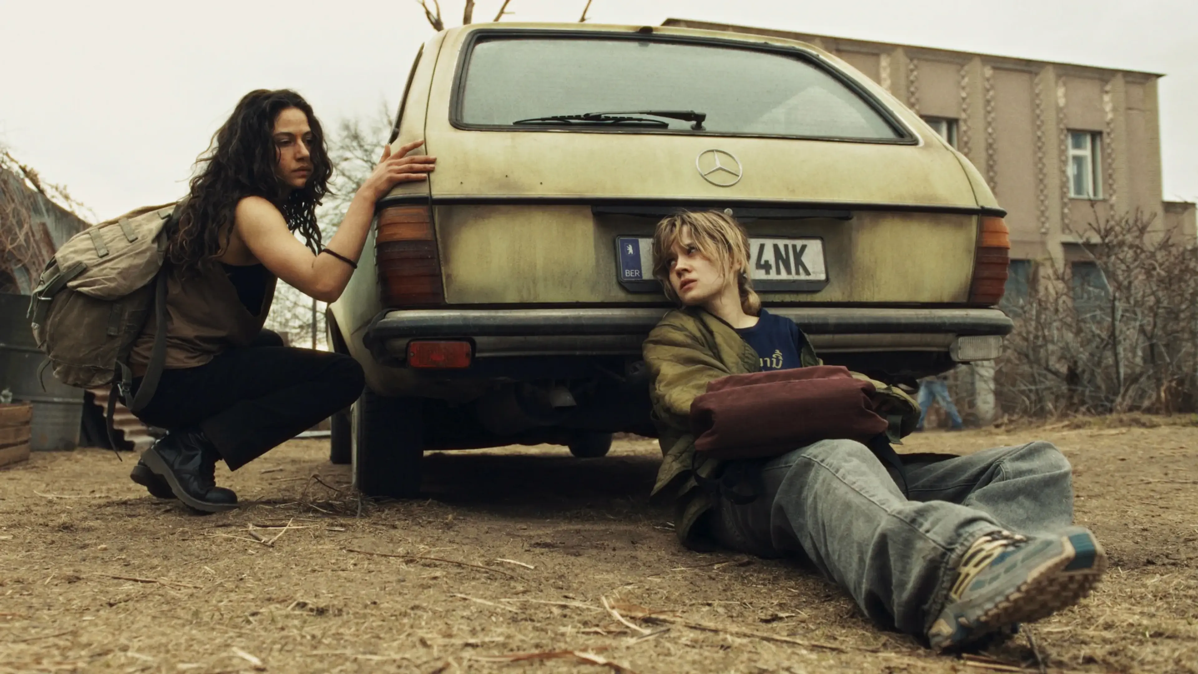 Bea and Phoebe shelter beside an old car in City of Blood.