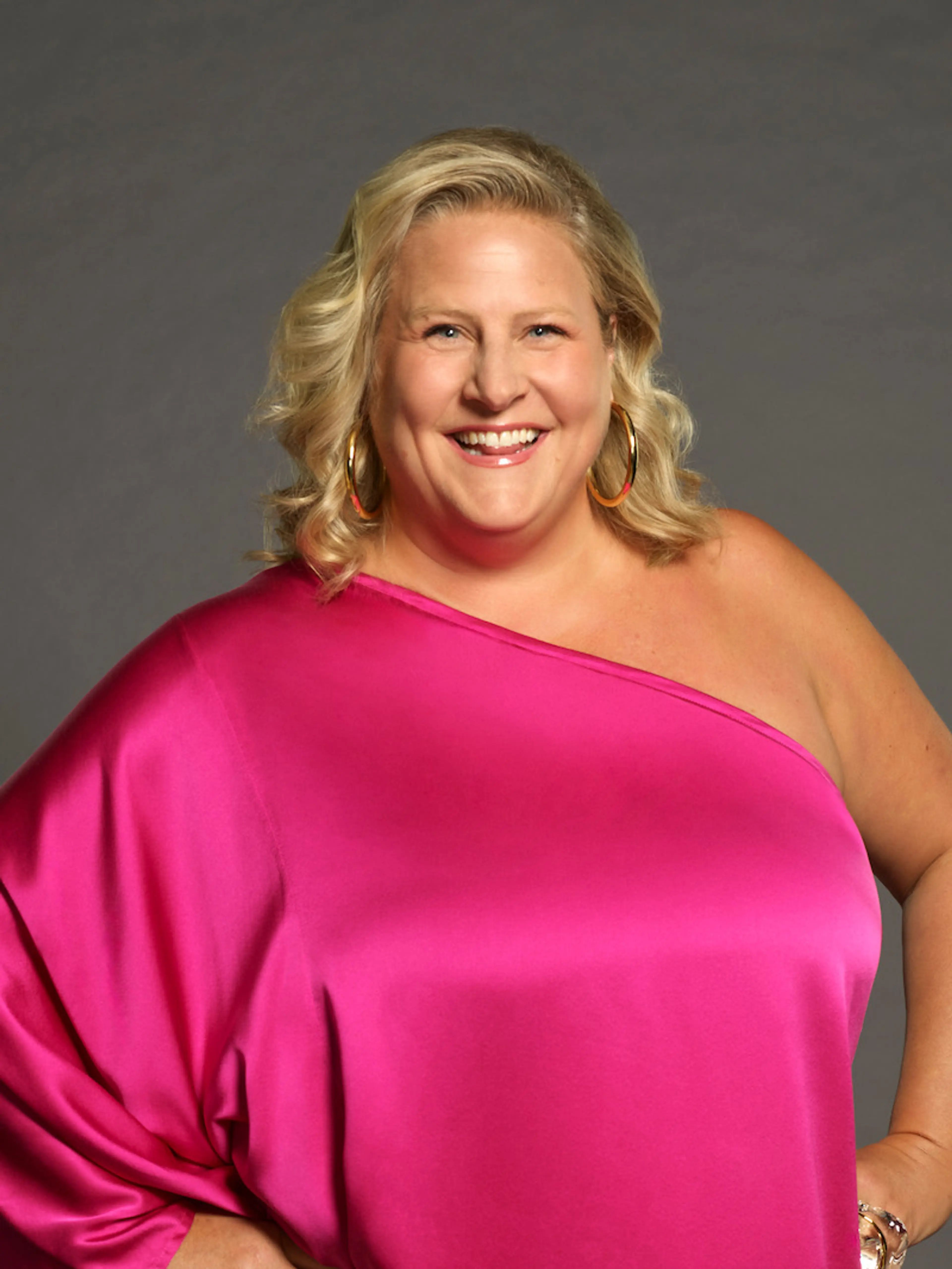 Bridget Everett smiles in a bright pink dress for Celebrity Million Dollar Secret.