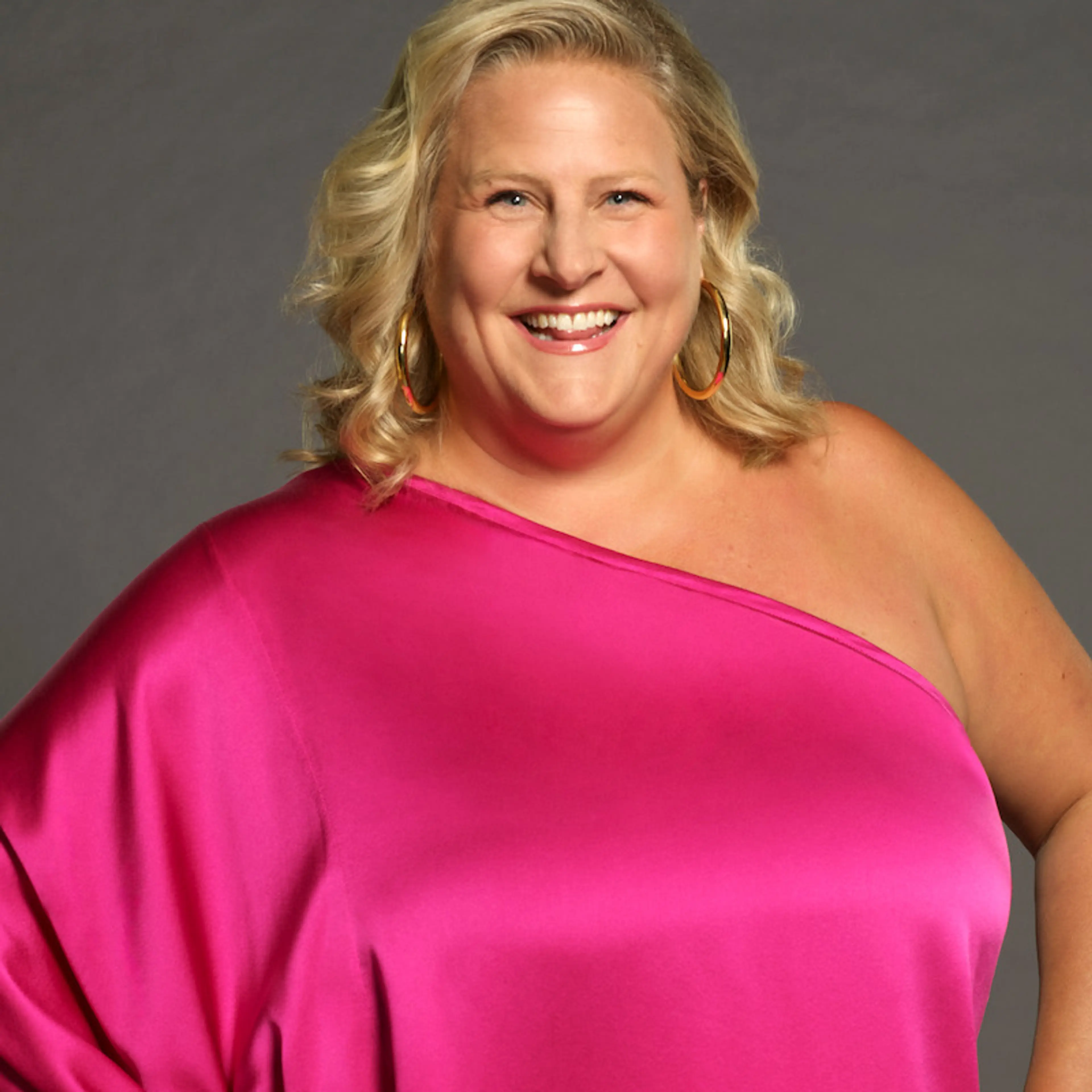 Bridget Everett smiles in a bright pink dress for Celebrity Million Dollar Secret.