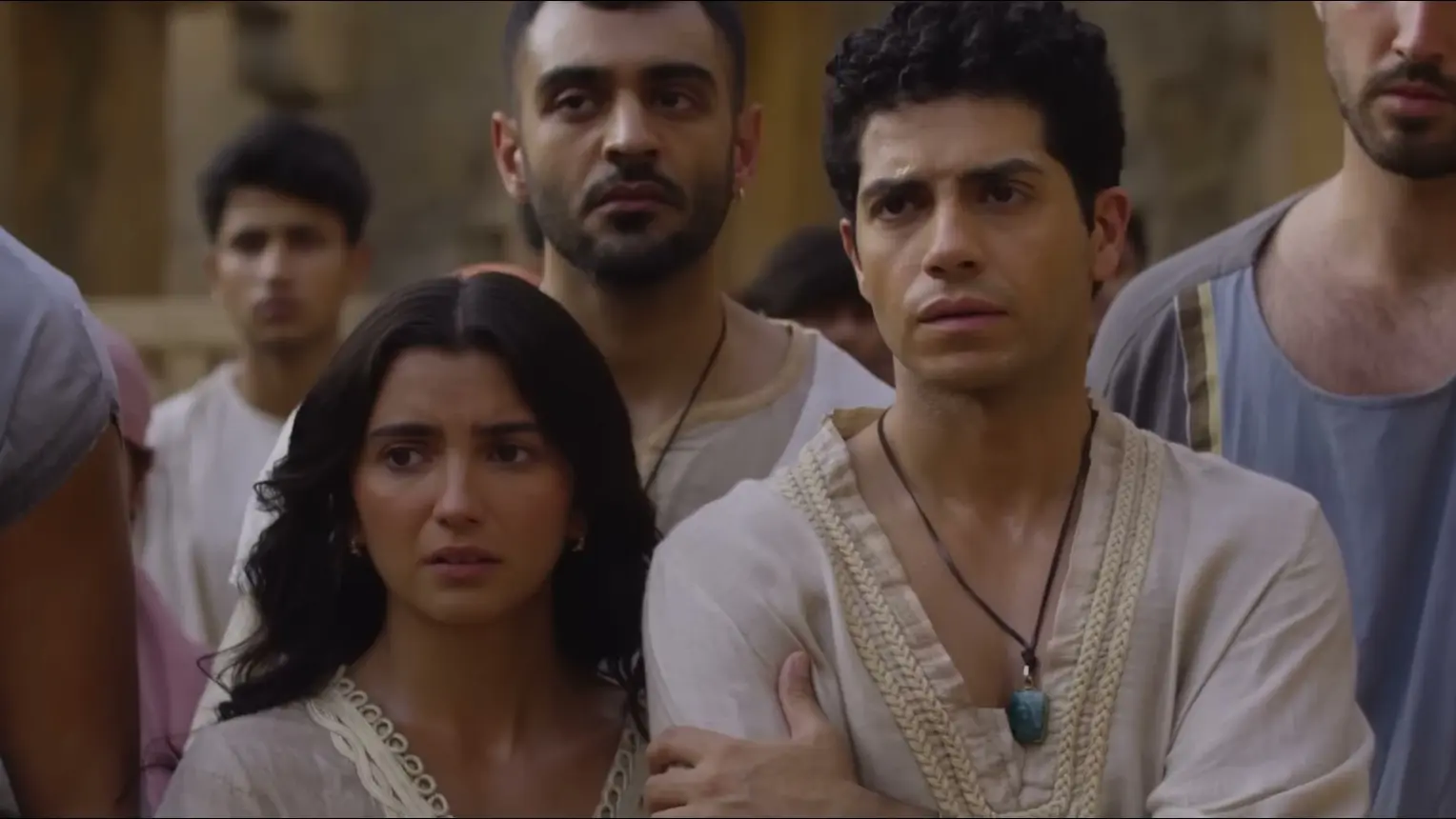 Mena Massoud as Daniel stands with Susanna and other young exiles in Babylon.