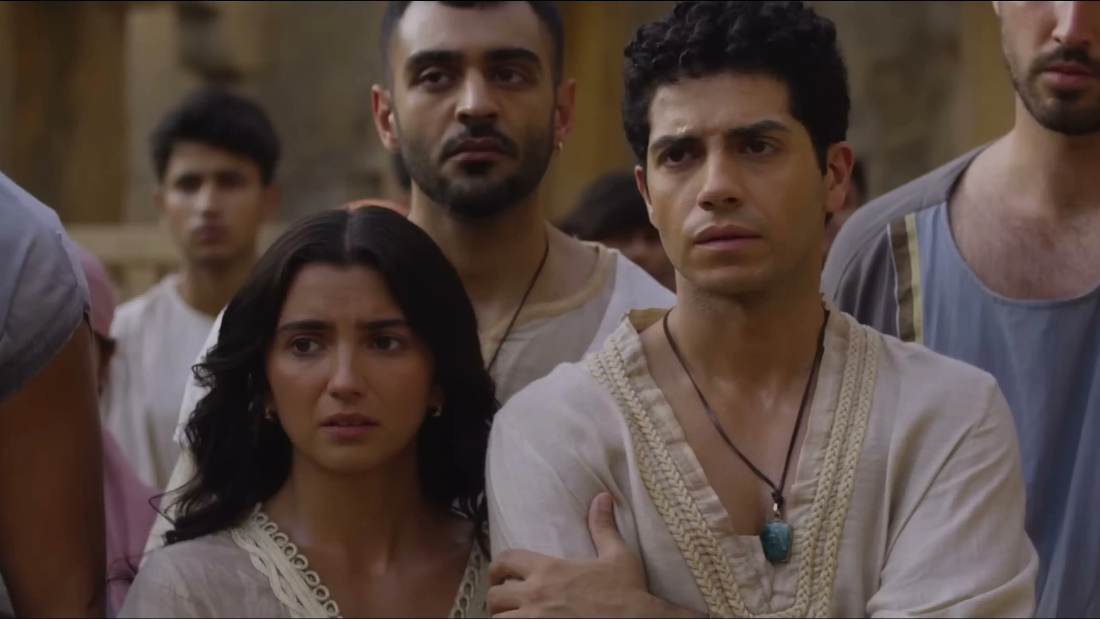 Mena Massoud as Daniel stands with Susanna and other young exiles in Babylon.